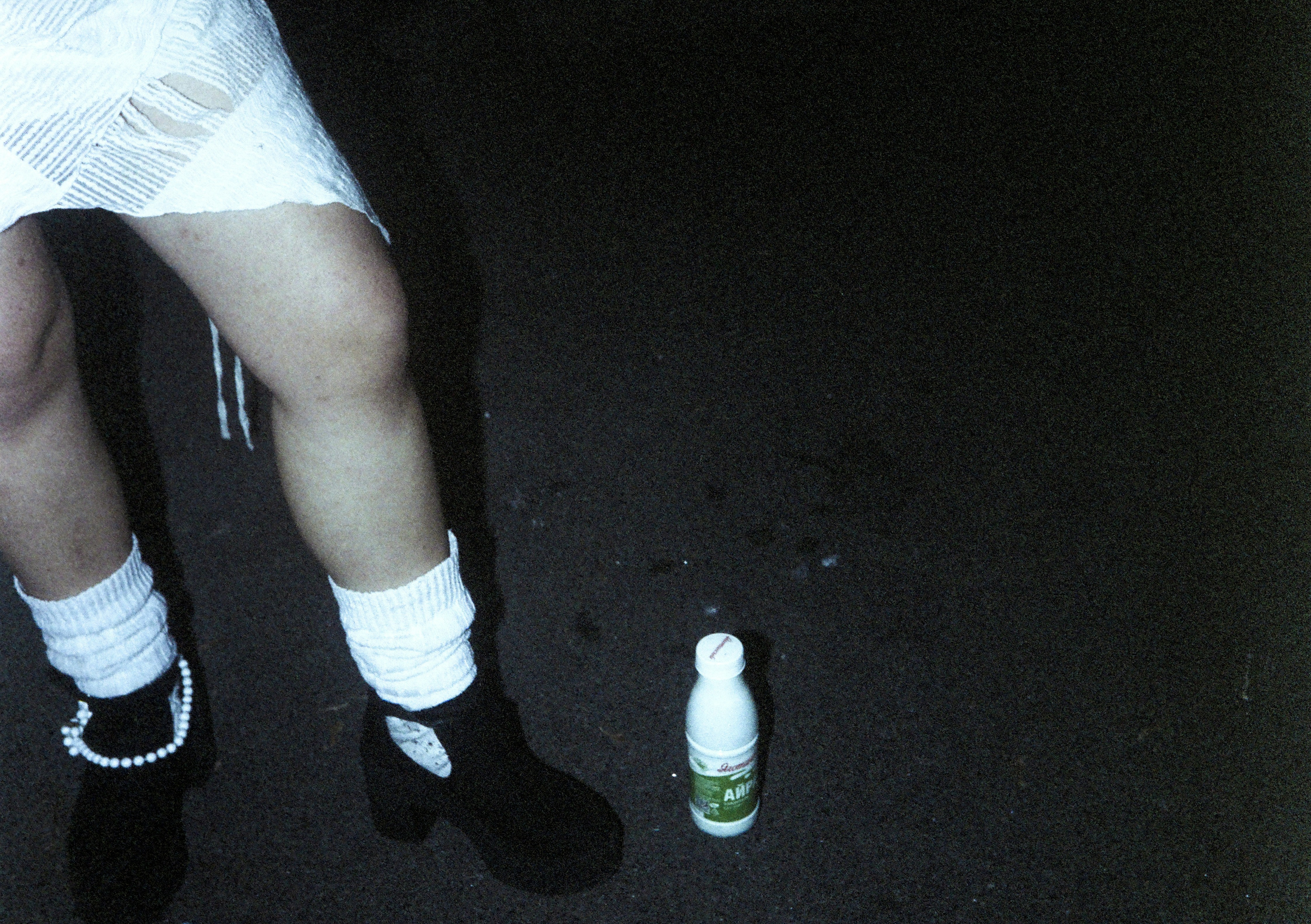 Frauenbeine mit weißen Socken und Stiefeln in der Nähe der Flasche
