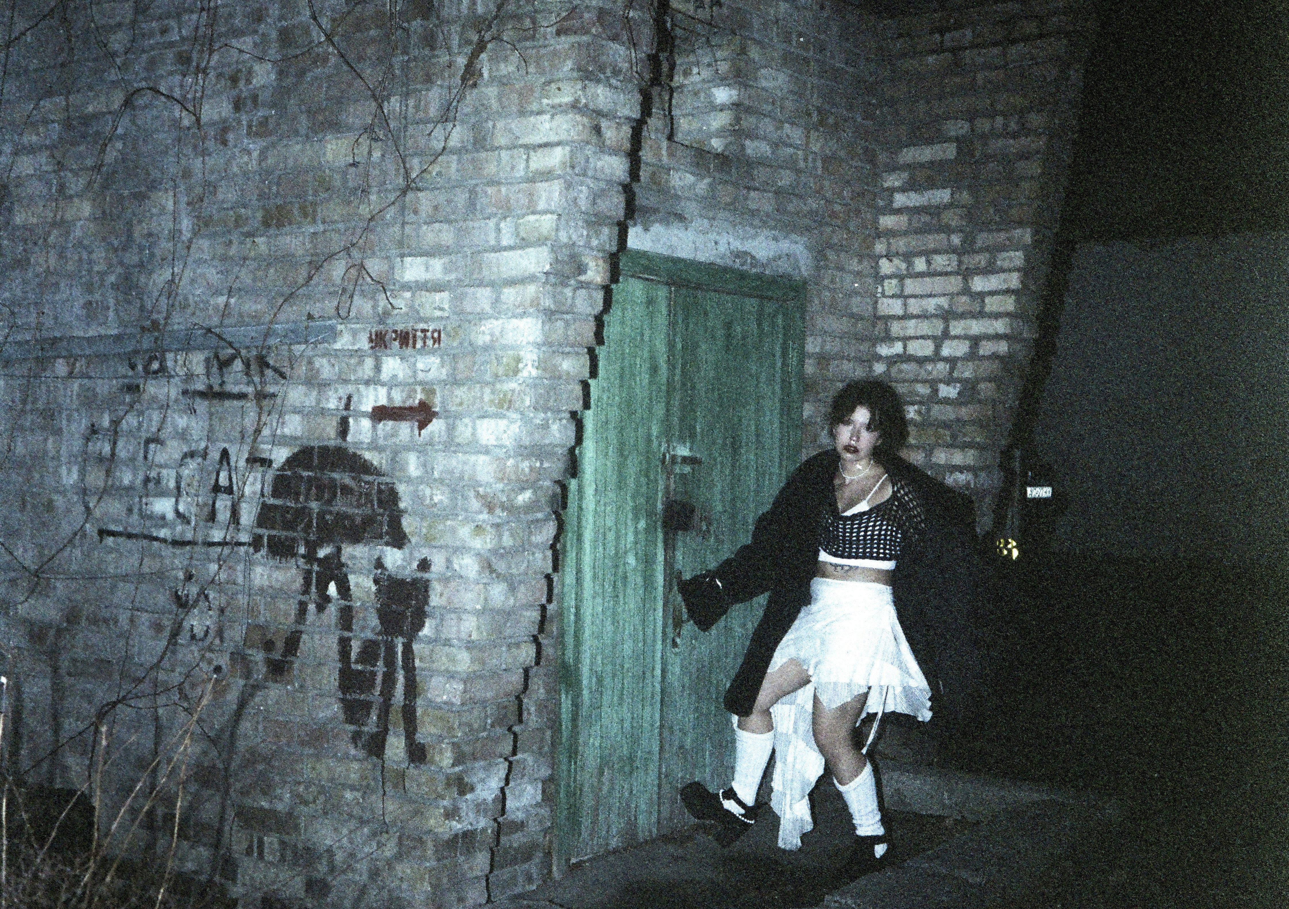 Woman in skirt and top by green door