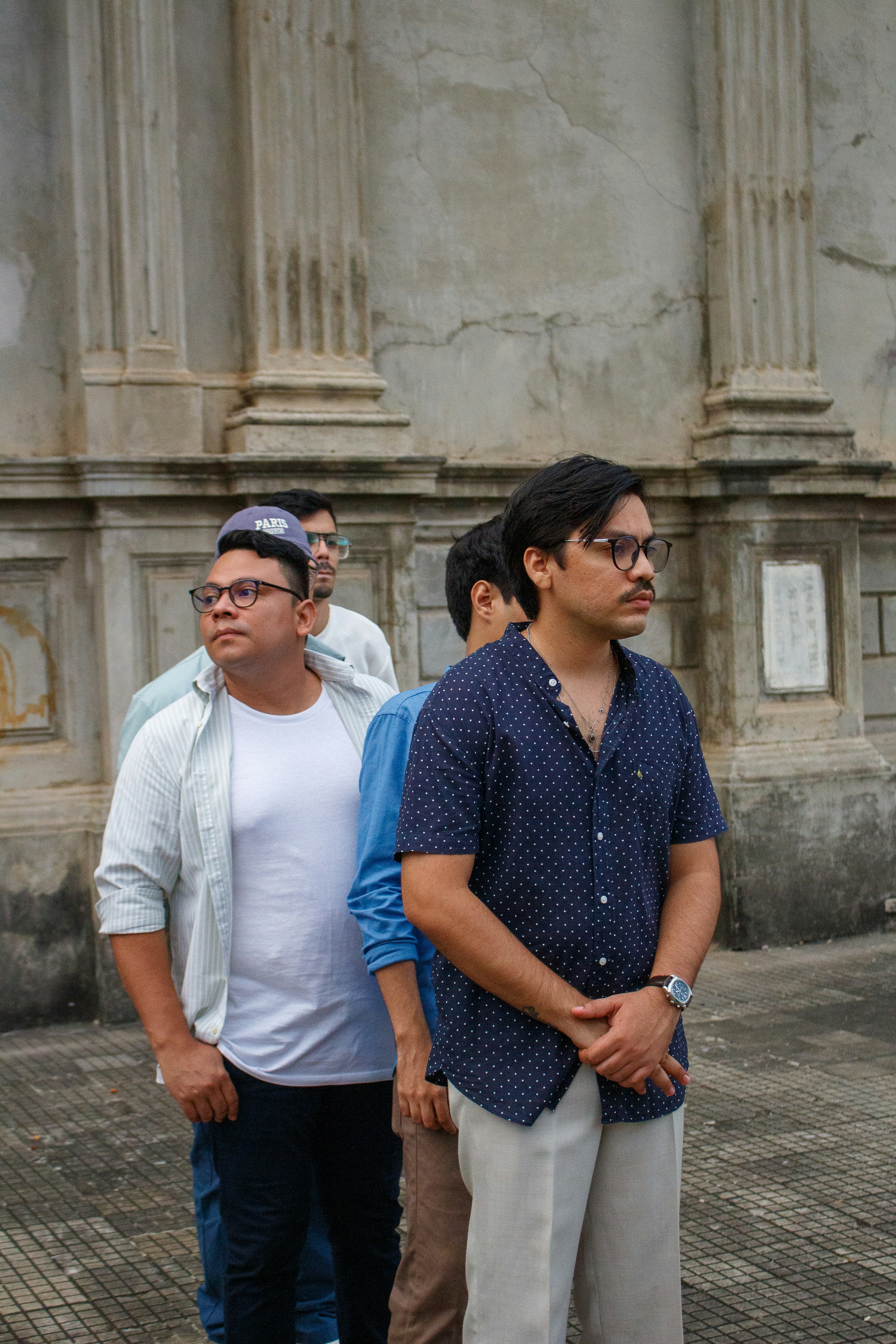 Cuatro hombres parados en una fila al aire libre