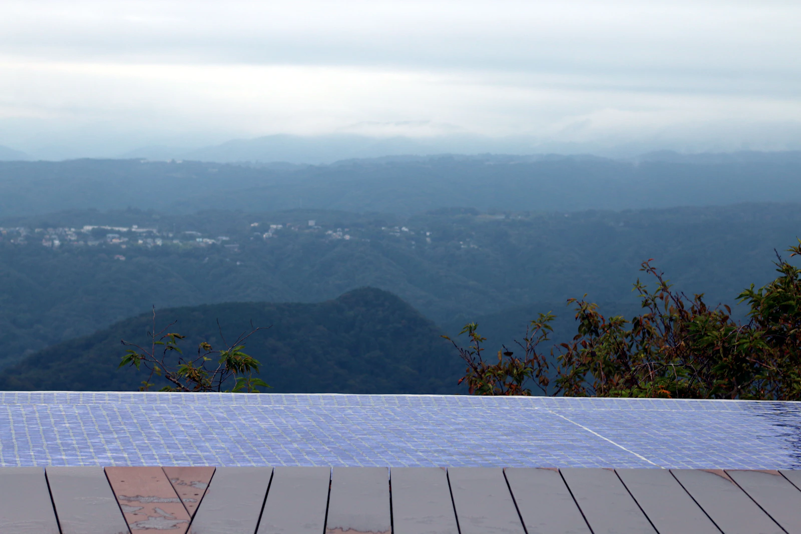 Infinity pool overlooking misty mountains and a distant town