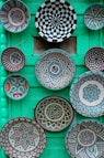 Colorful decorative plates arranged on a green wall.