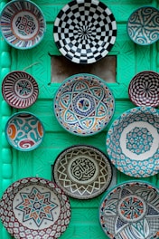 Colorful decorative plates arranged on a green wall.
