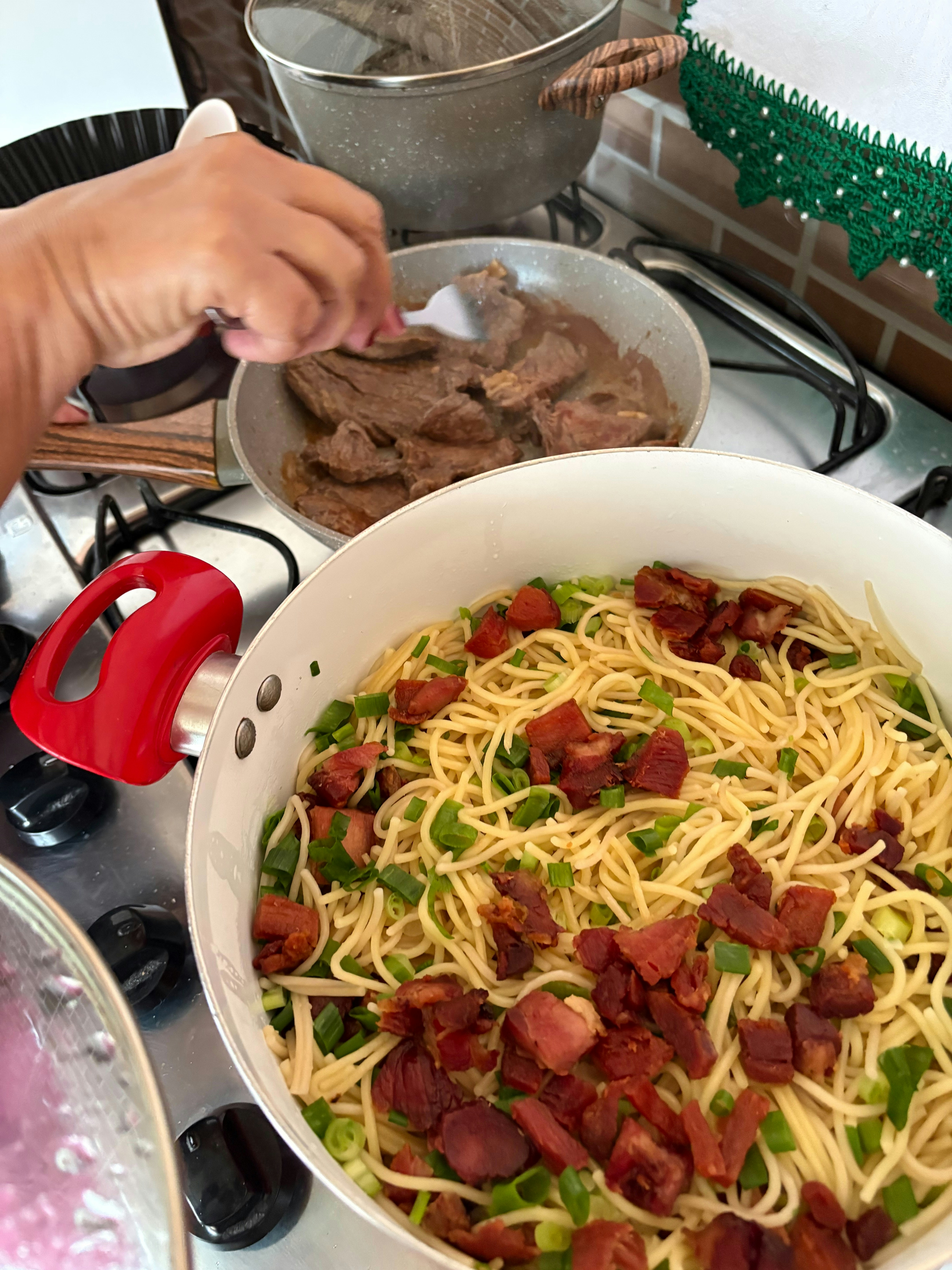 Spaghetti with bacon and green onions being prepared.
