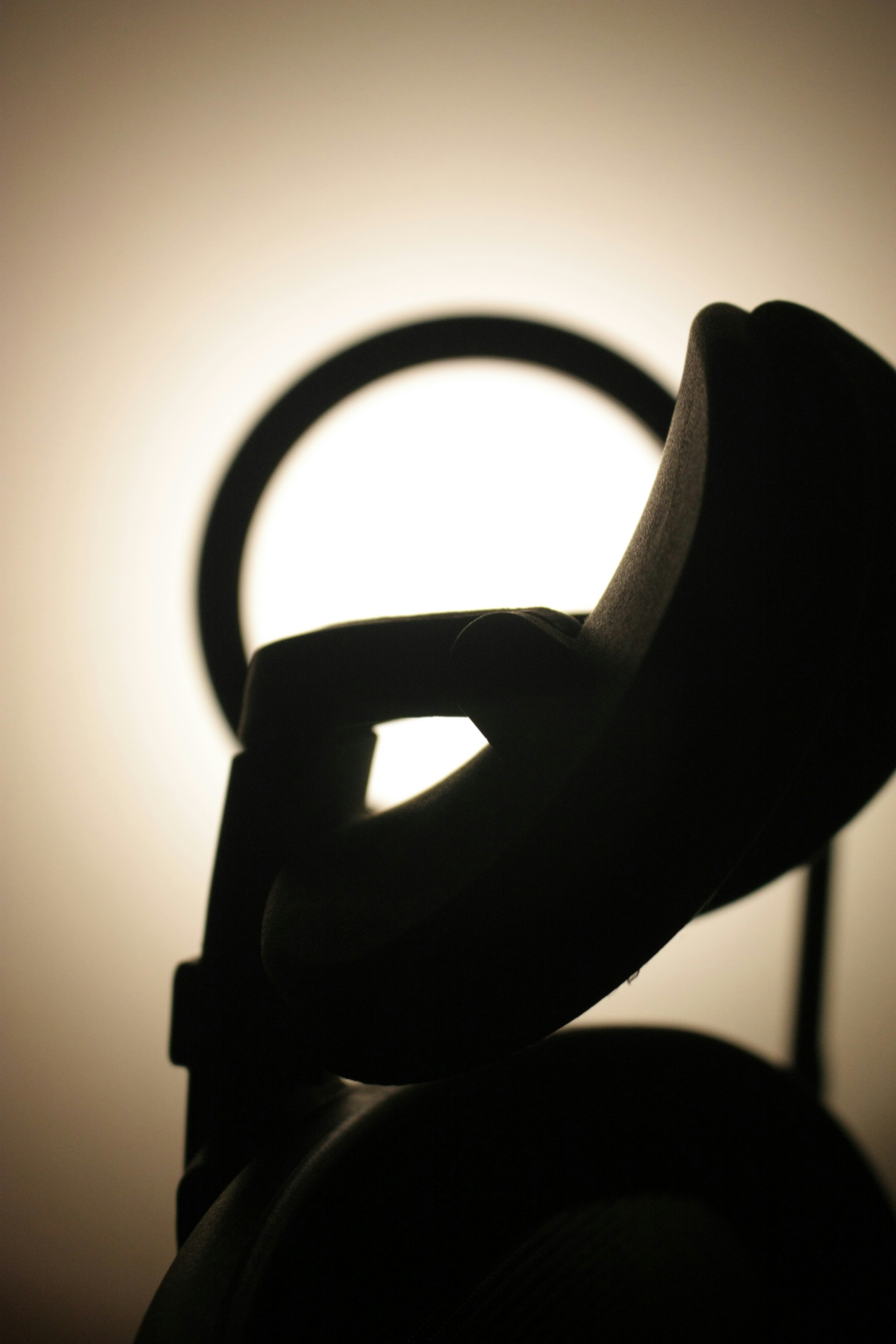 Silhouette of headphones with a circular light behind