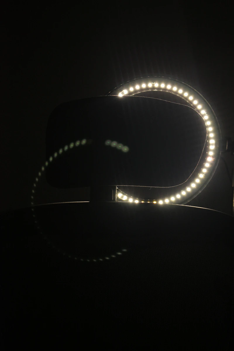 Studio LED ring light glowing on a featureless dark background.