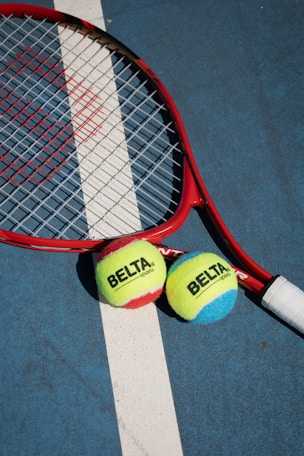Tennis racket and two balls on court