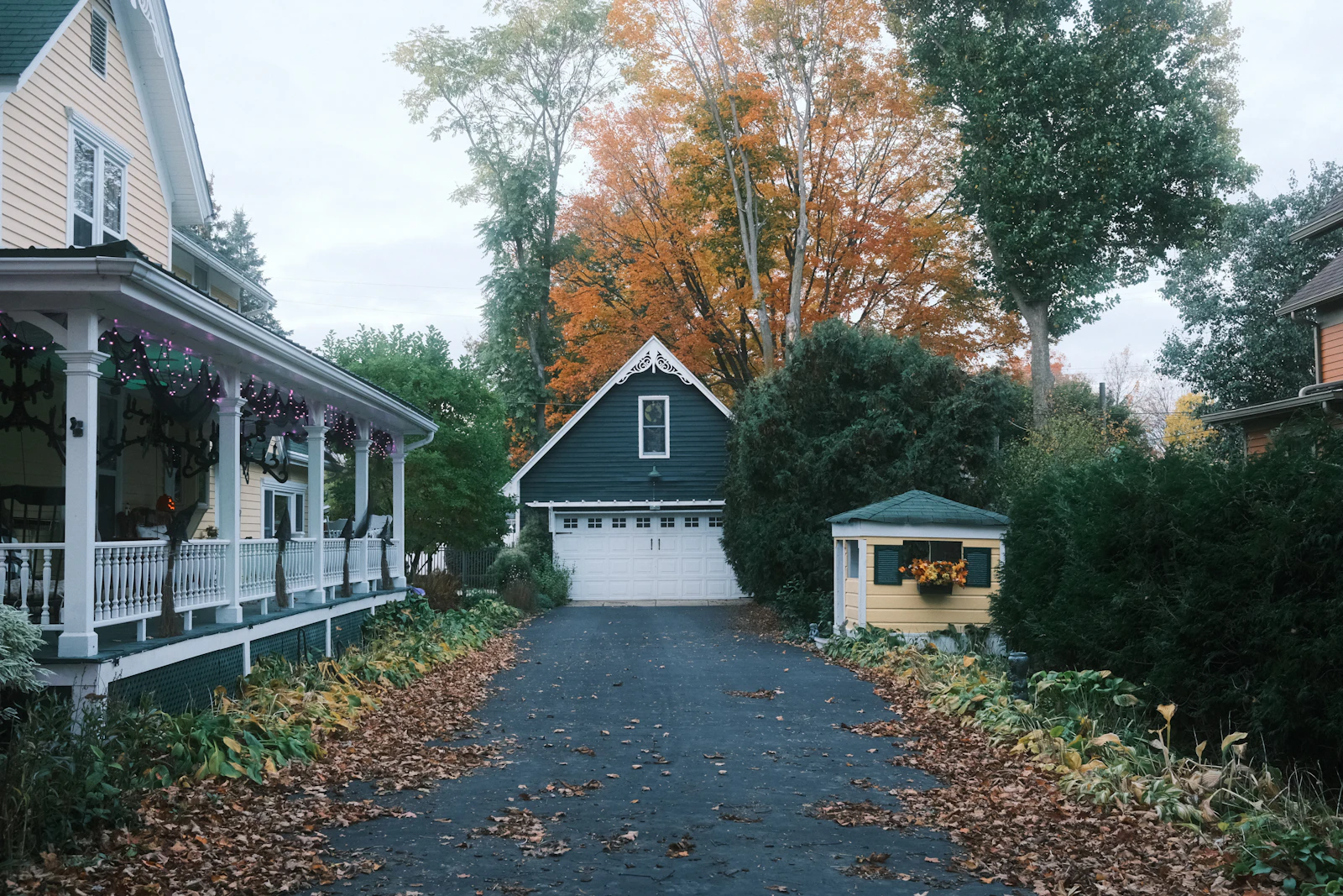 A driveway leading to a detached garage under autumn trees.