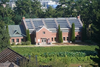 Brick building with a large glass roof surrounded by greenery.