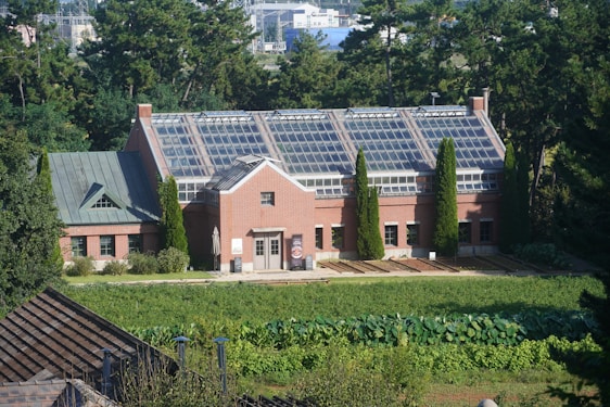 Brick building with a large glass roof surrounded by greenery.