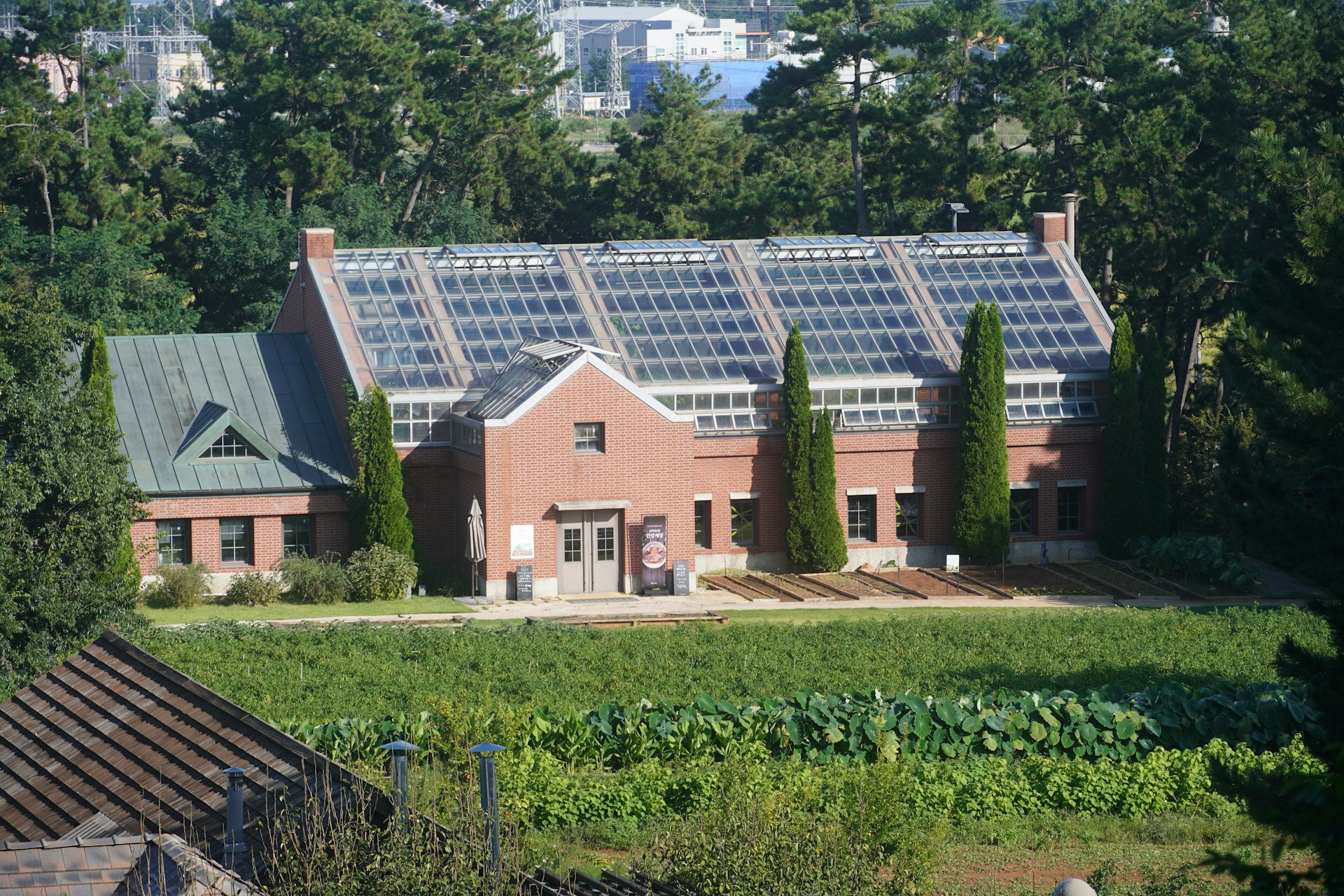 Brick building with a large glass roof surrounded by greenery.