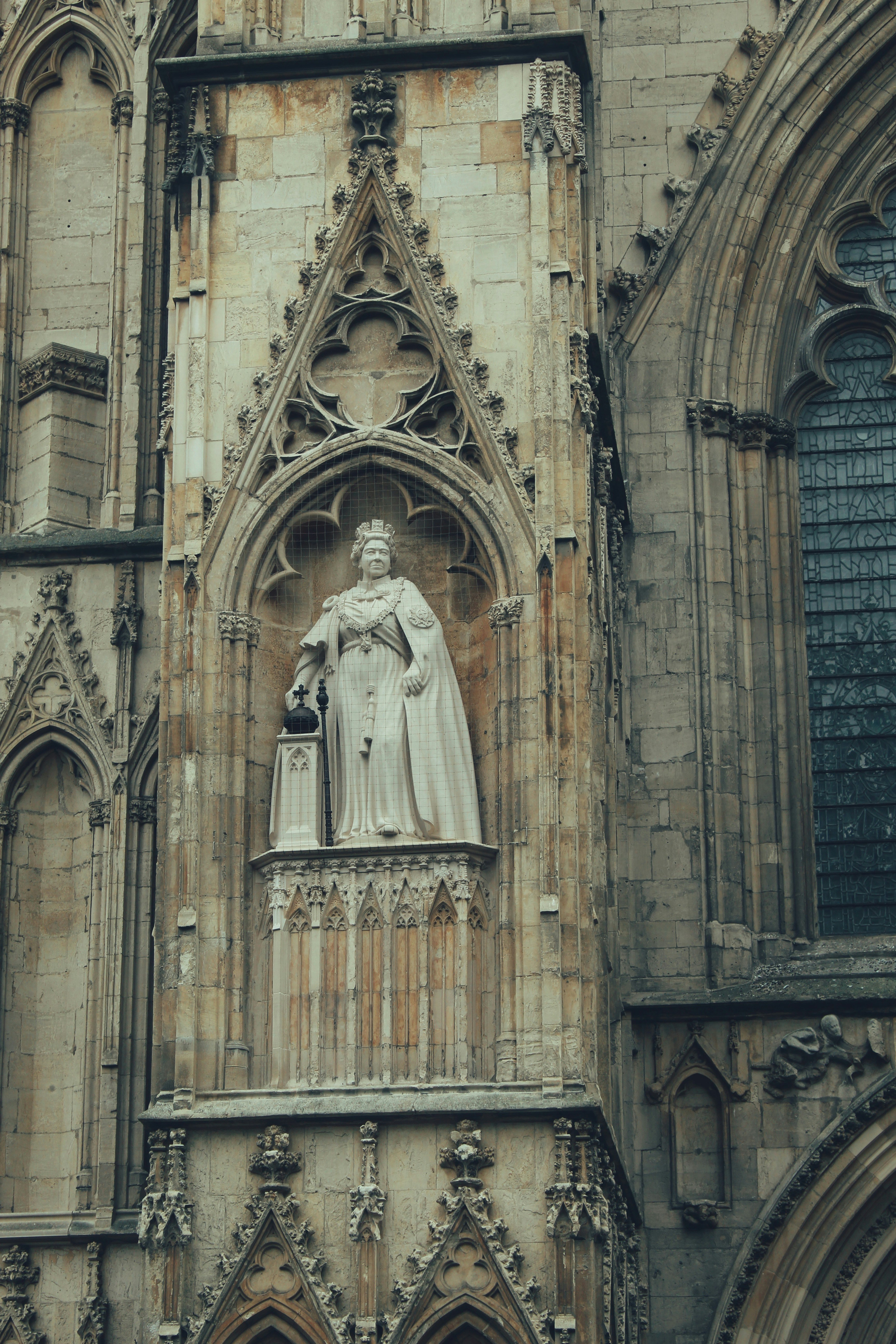 Statue of a regal figure on a stone building facade.