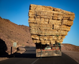Truck overloaded with hay bales on a desert road.