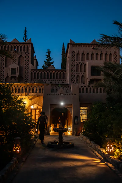 The courtyard of a Moroccan riad lit by lanterns at dusk, set for an evening meal