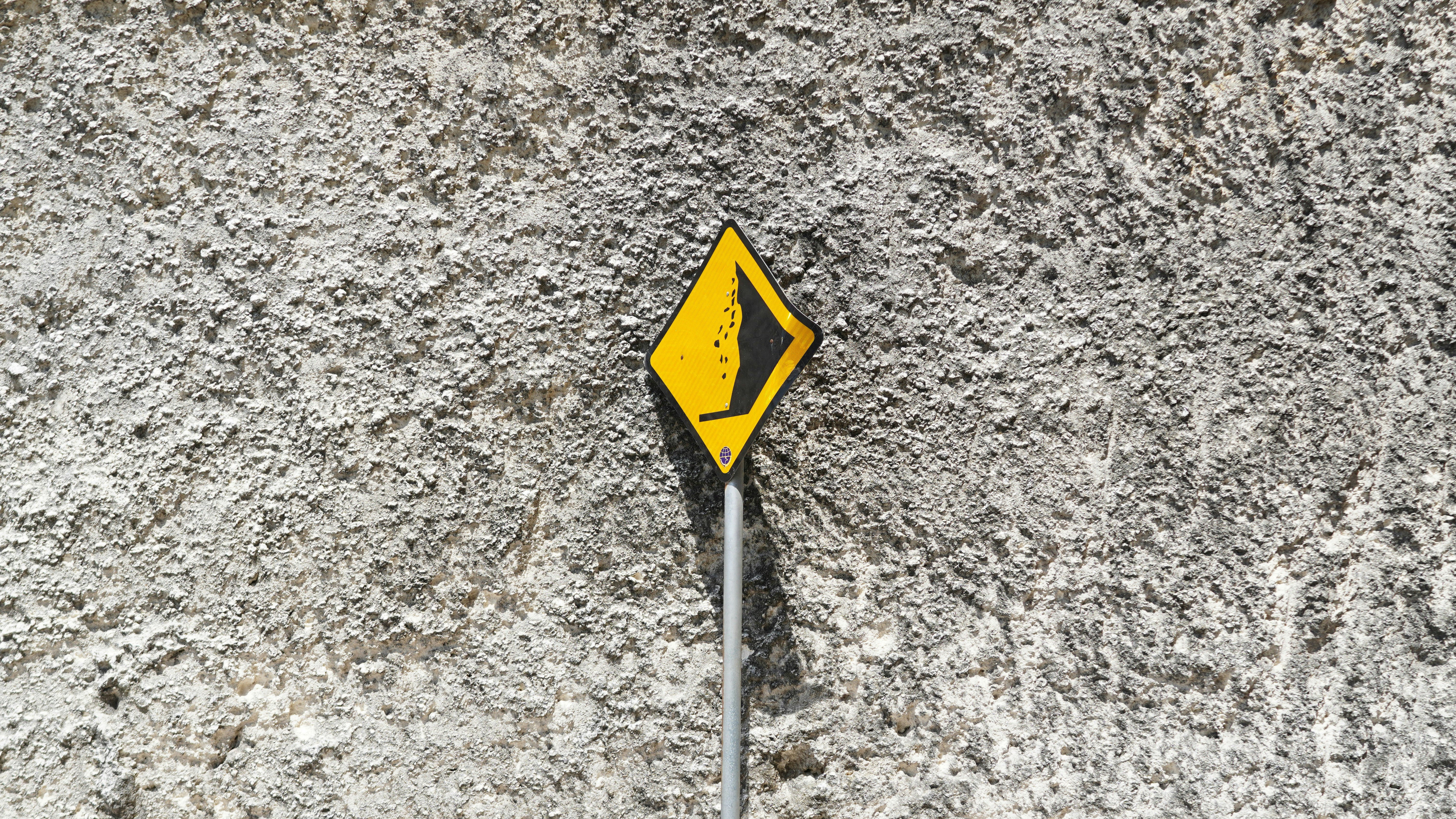 Yellow diamond sign against a textured wall