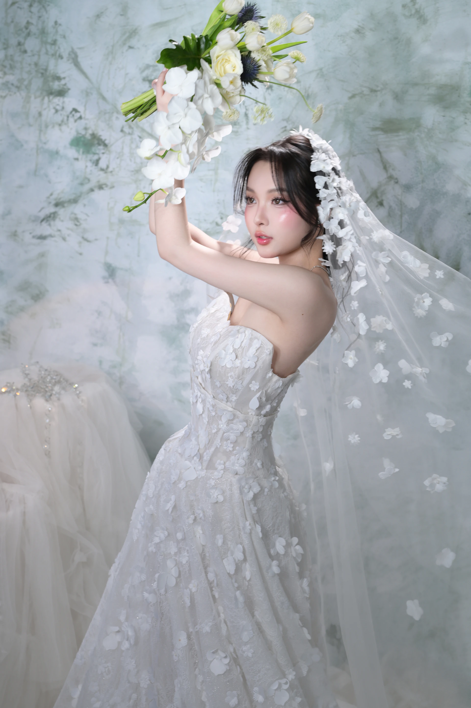 Bride in white dress holding a bouquet with veil