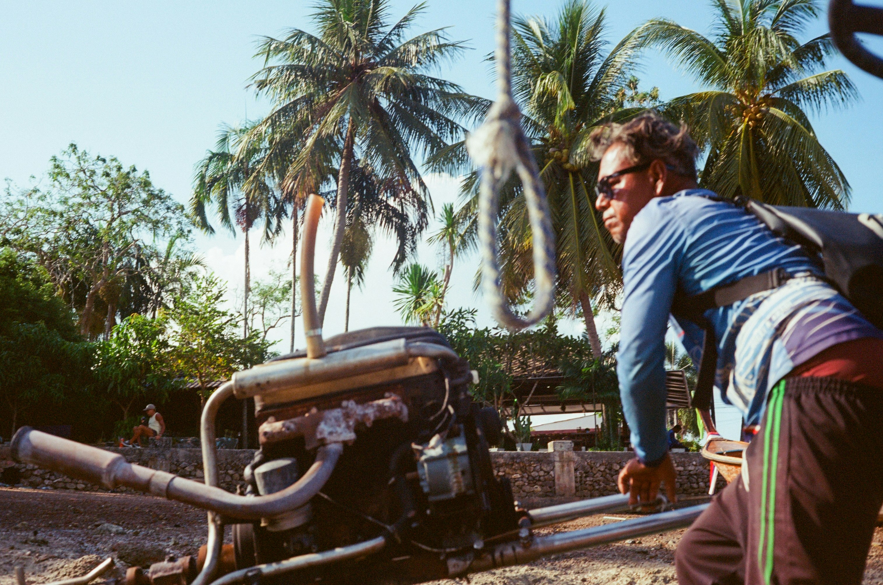 Man by boat engine with palm trees in background