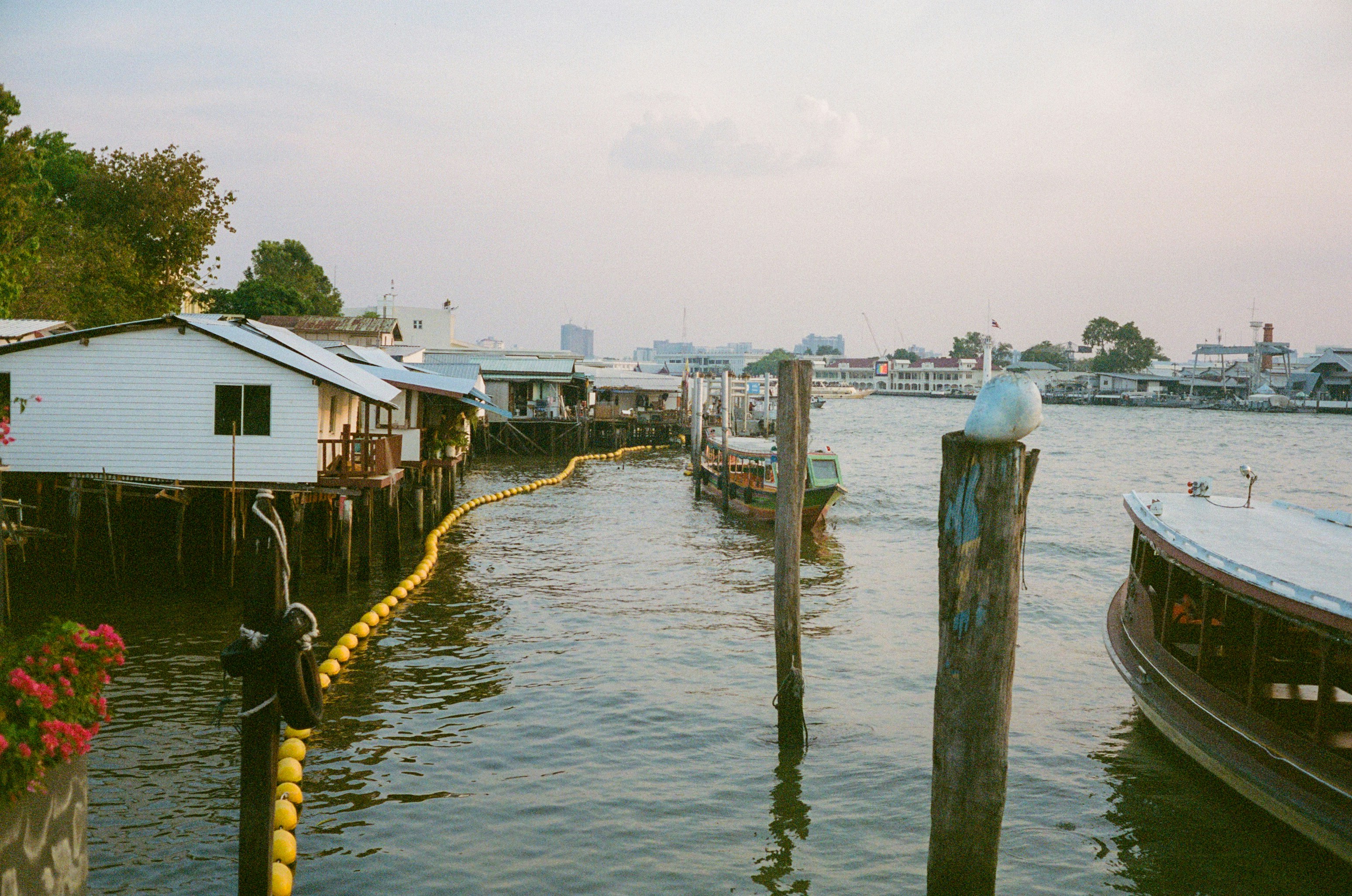 Las casas sobre pilotes bordean un río con barcos atracados cerca.