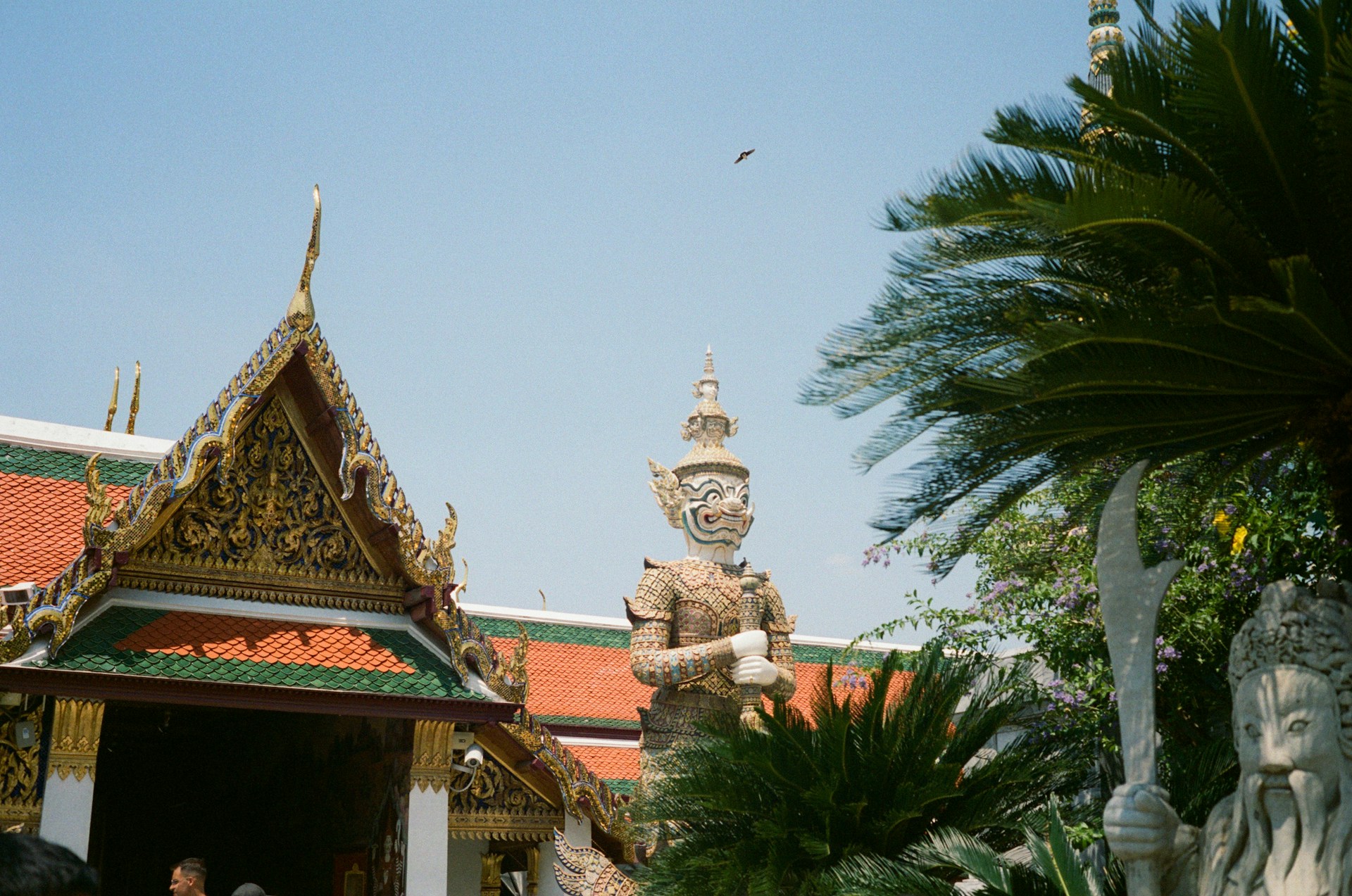 Ornate temple building with guardian statues and palm trees.