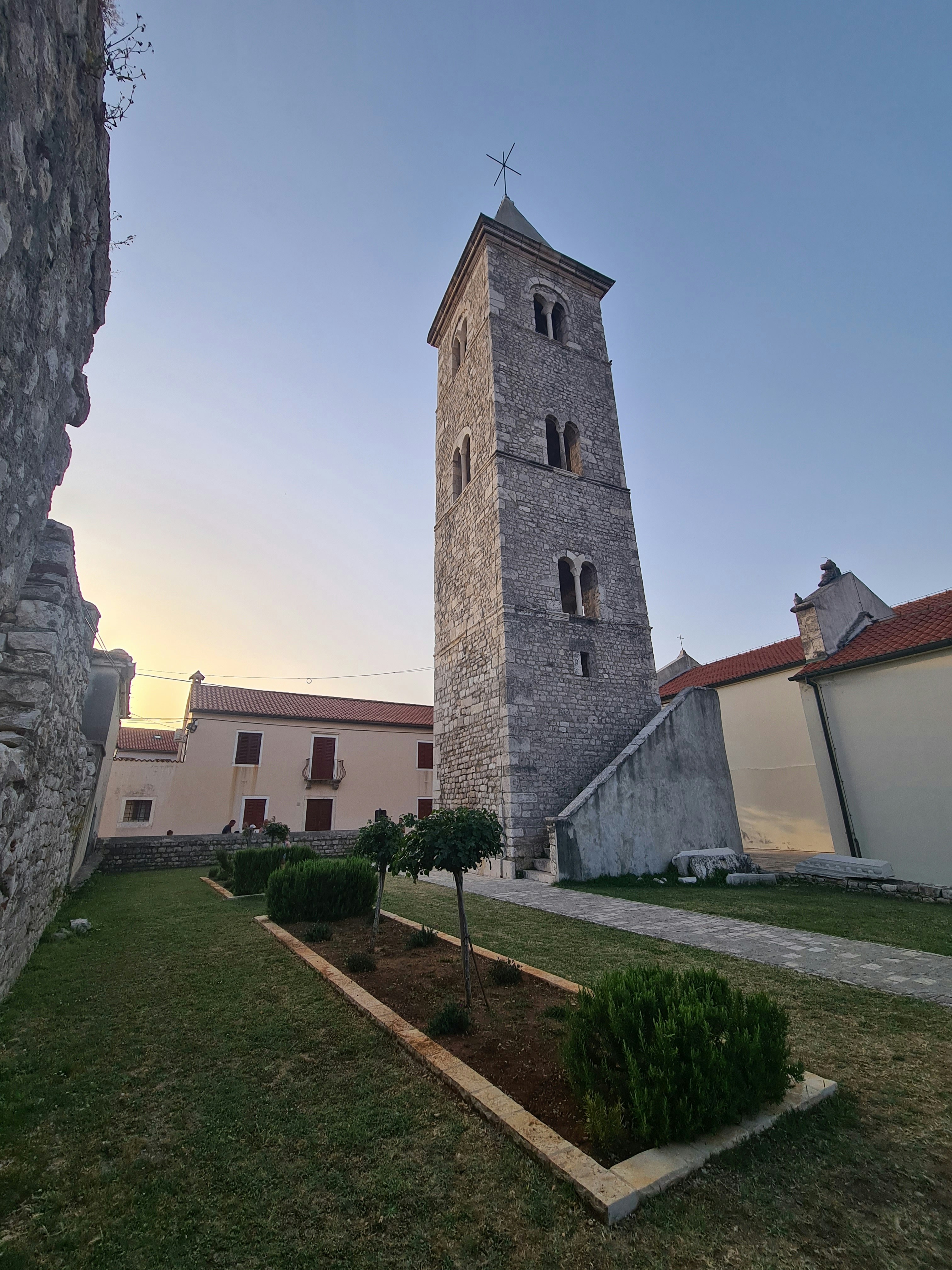 Stone bell tower next to buildings under clear sky