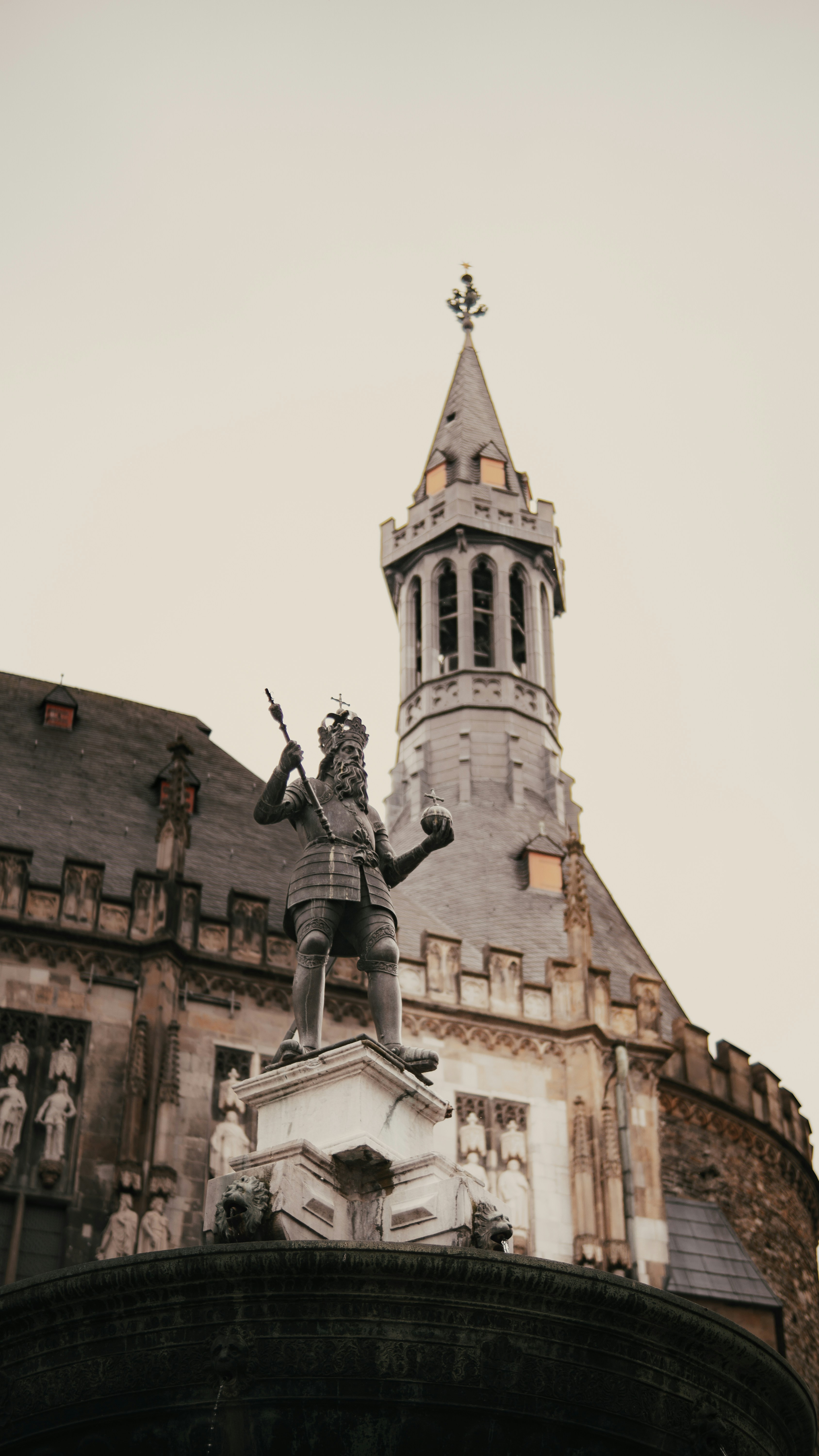 Statue of a king holding orb and scepter with building.