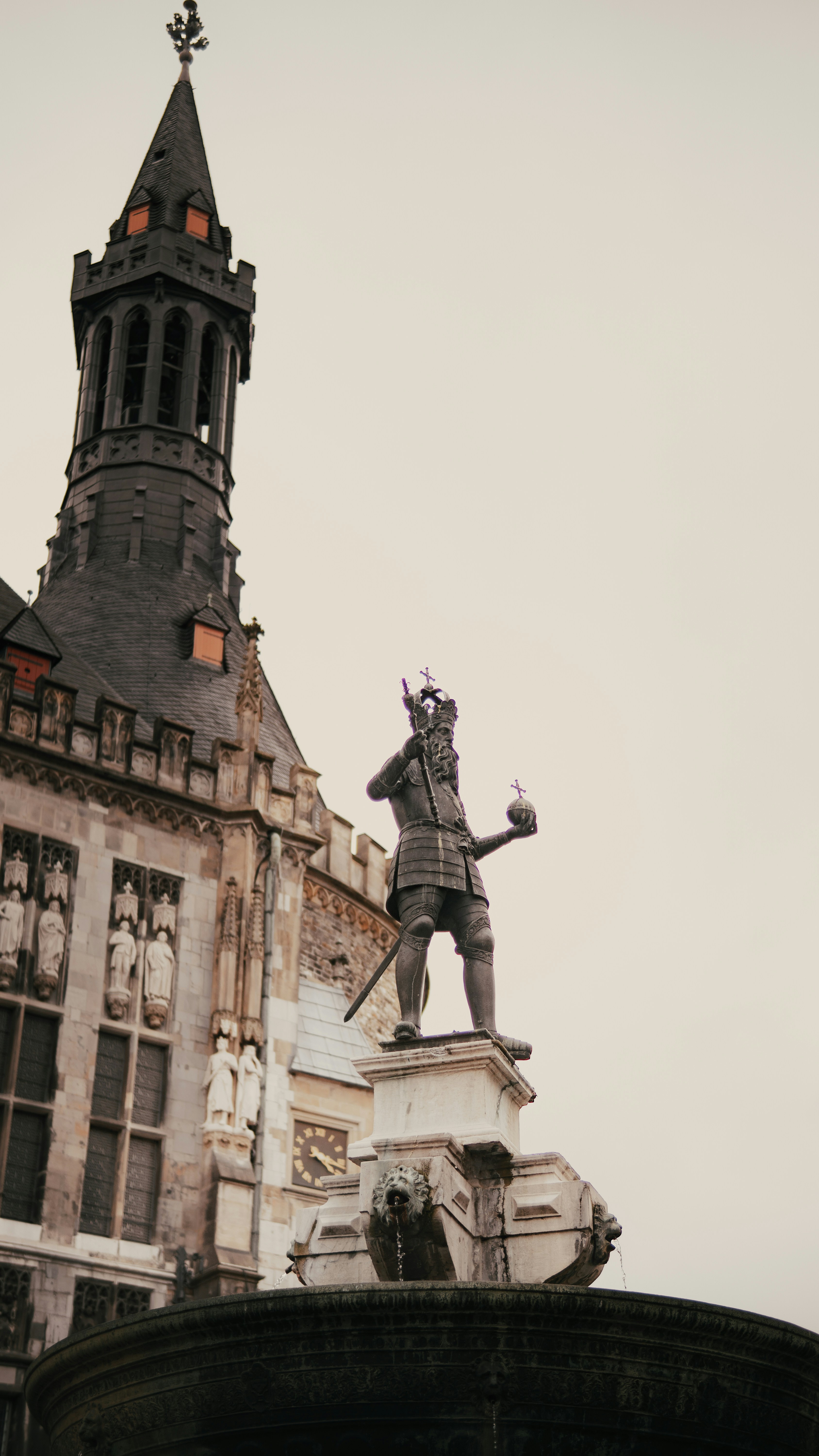Statue of a king holding orb on fountain near building