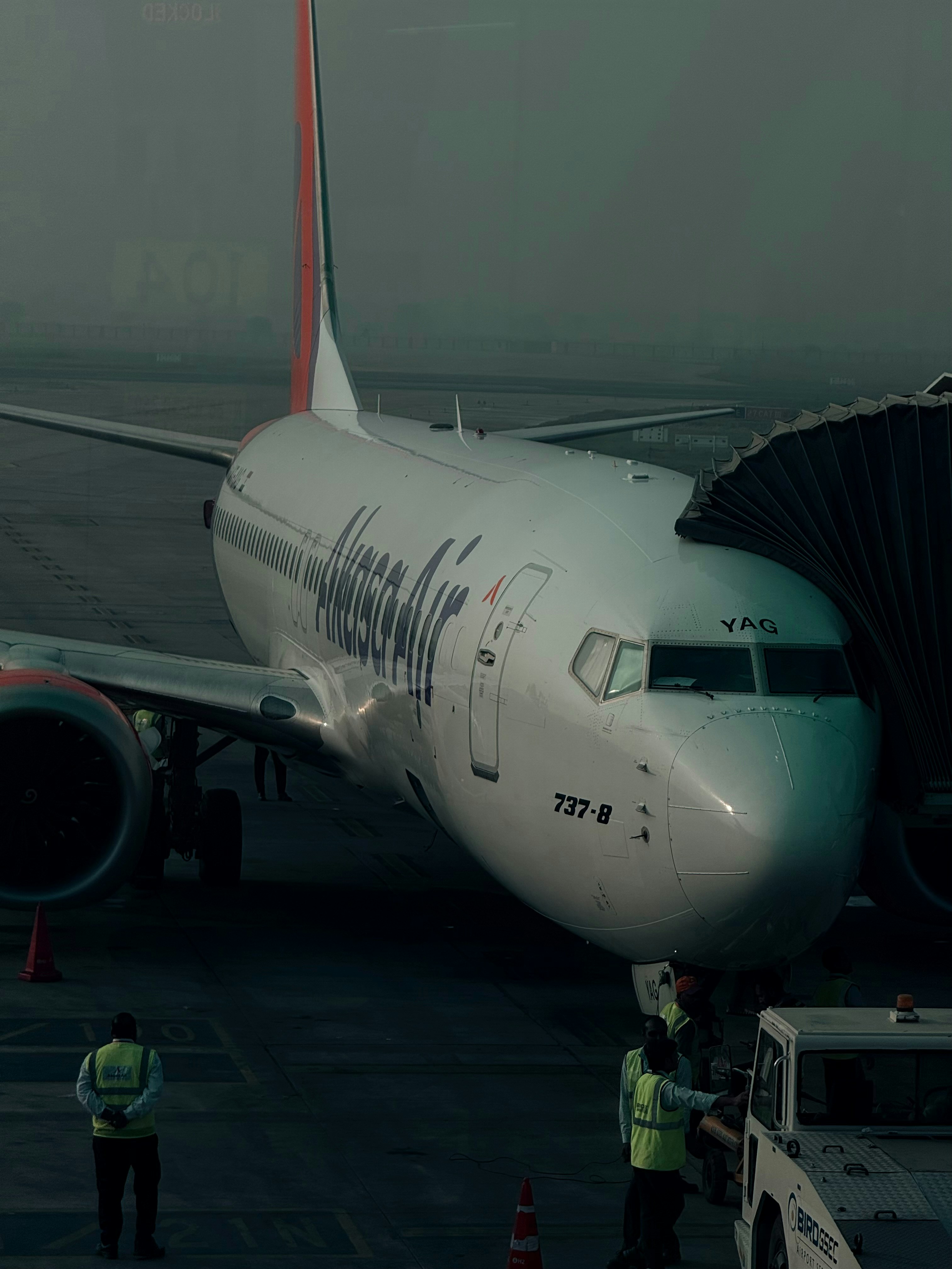 Airplane connected to a jet bridge at foggy airport