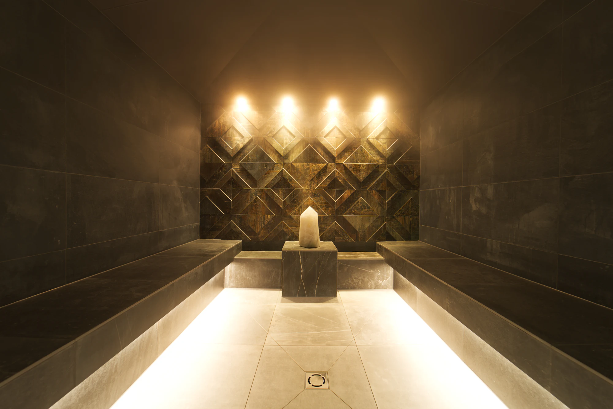 Candlelit steam room with warm stone benches at Lumina Wellness