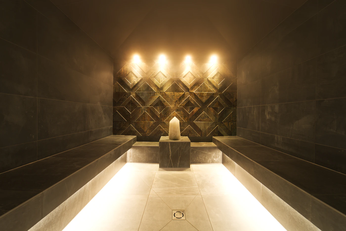Private treatment suite in dark marble lit with warm gold light