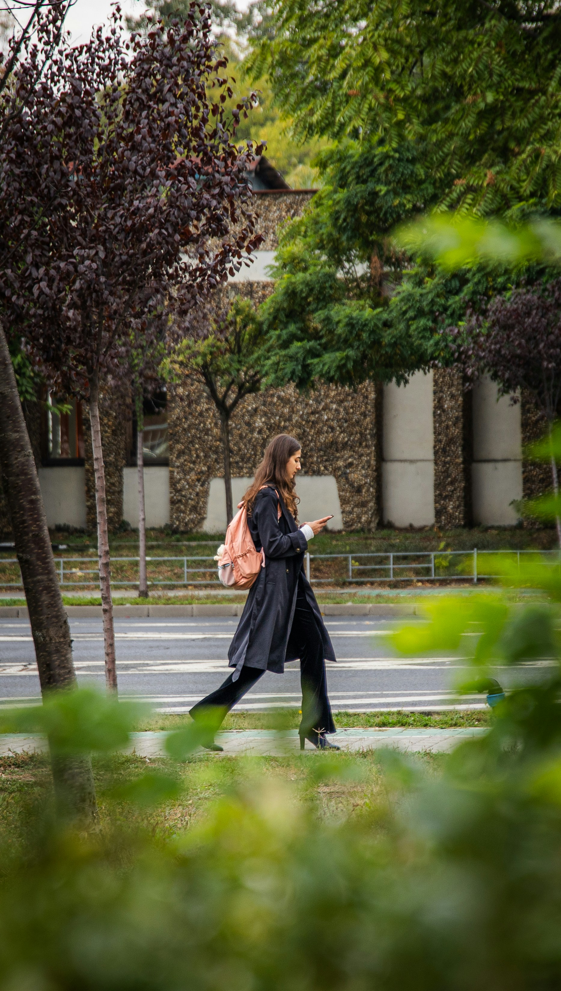 Una donna con uno zaino cammina tra edifici e alberi.