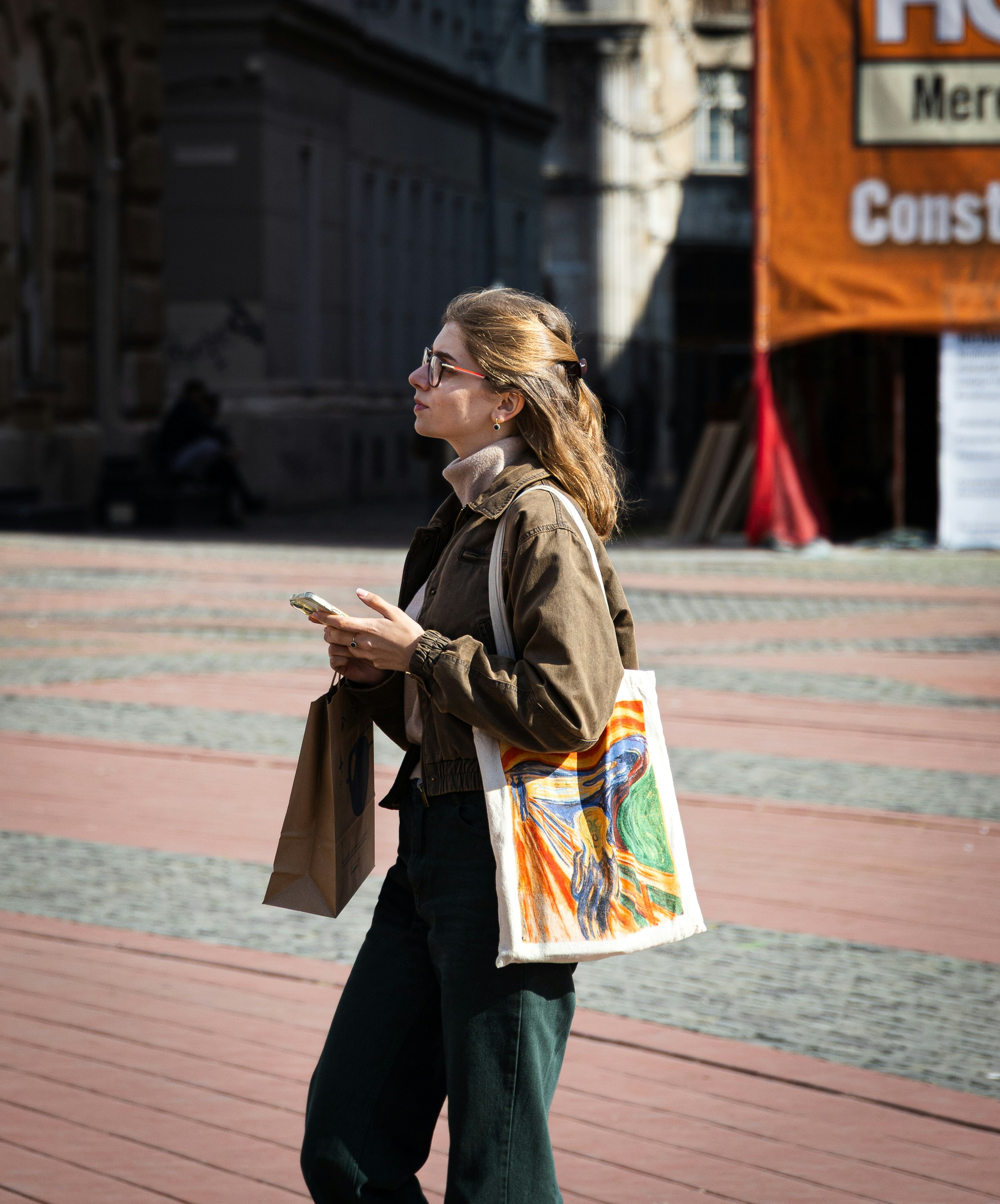 Donna che tiene il telefono e la borsa sulla strada della città