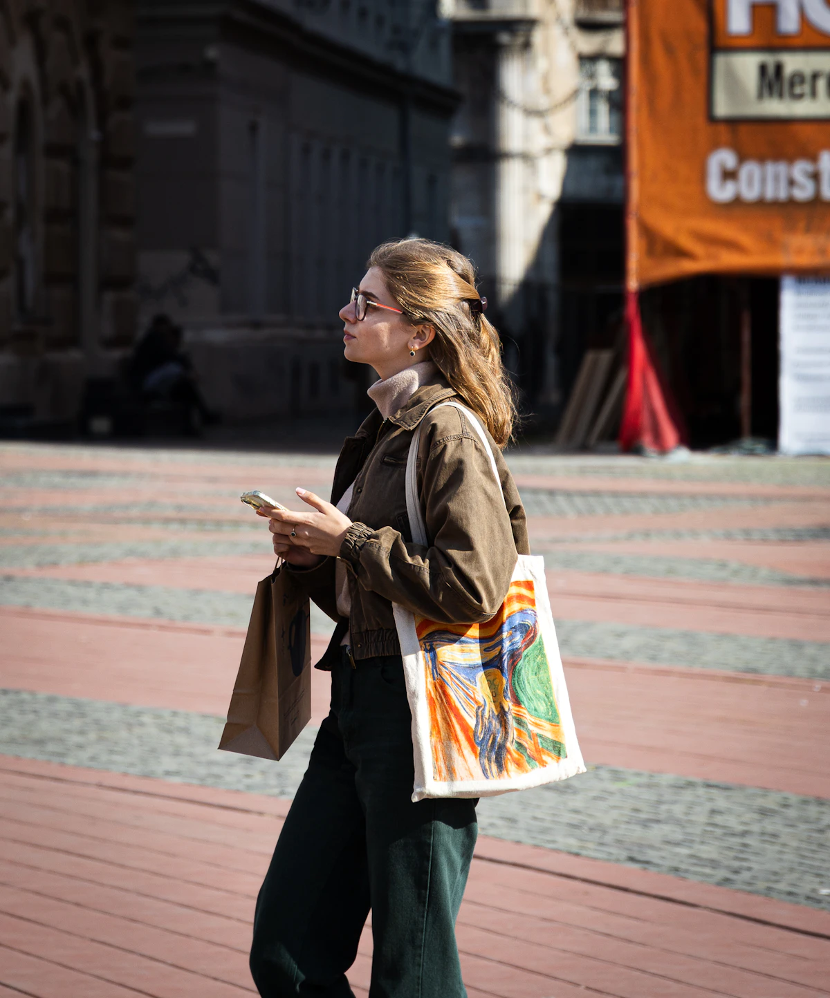 Woman carrying a bag while walking along a city street