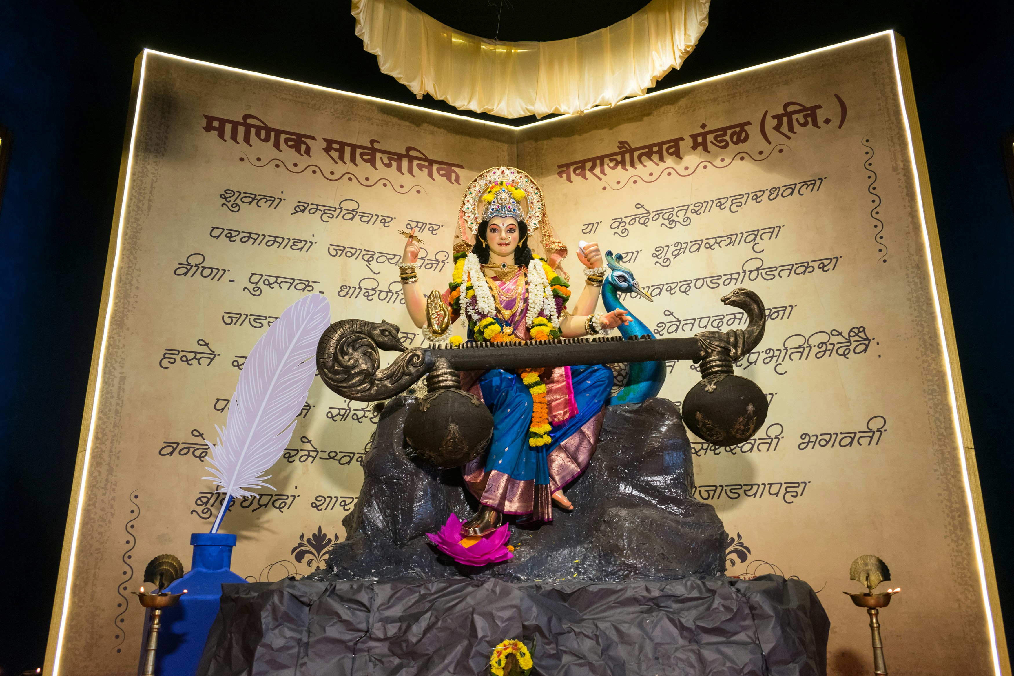 Goddess saraswati statue holding a veena with a peacock
