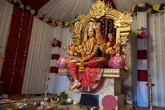 Goddess durga statue seated on a throne with offerings.
