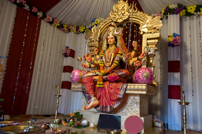 Goddess durga statue seated on a throne with offerings.