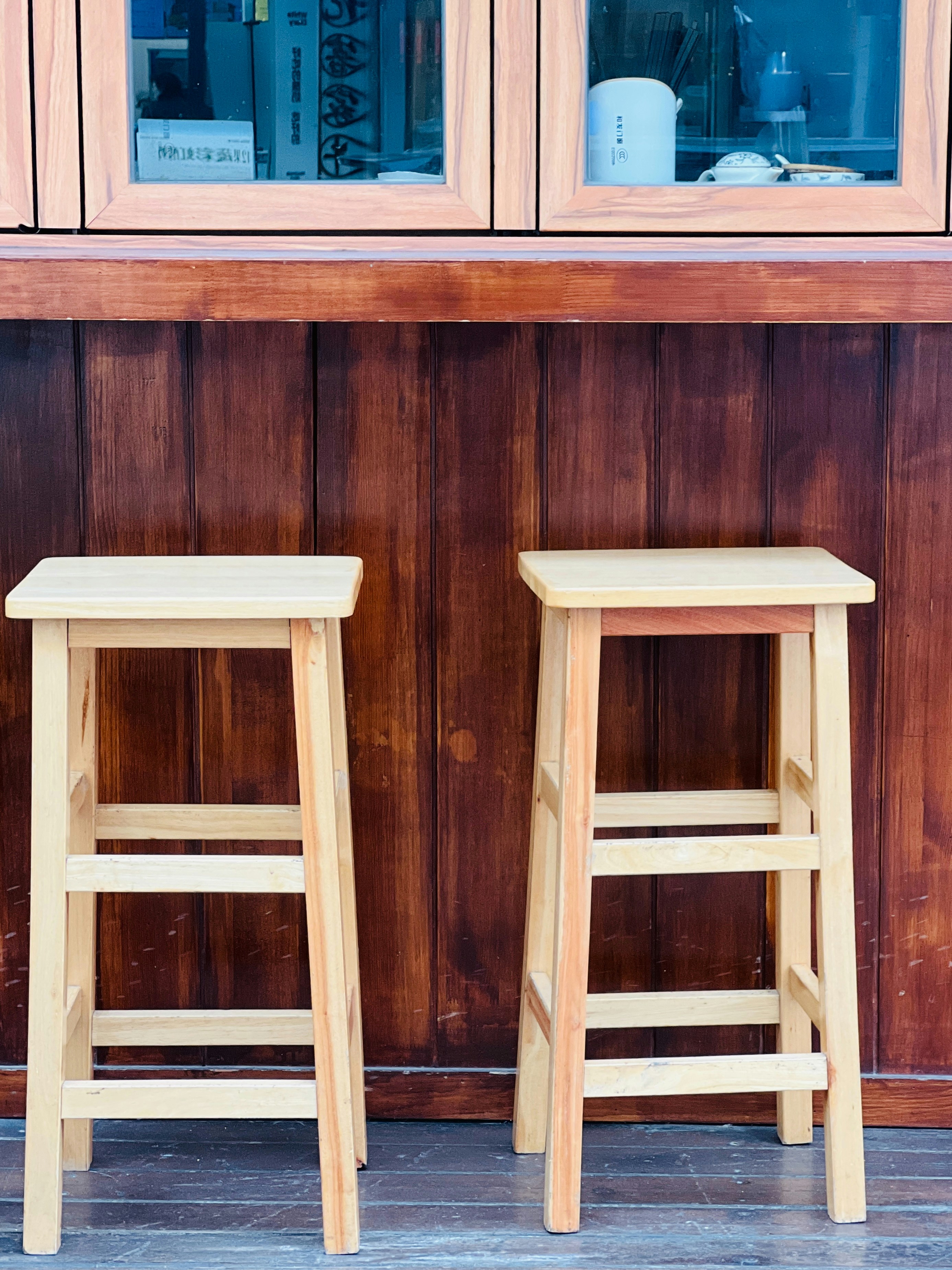 Zwei Barhocker aus Holz vor einer hölzernen Theke.