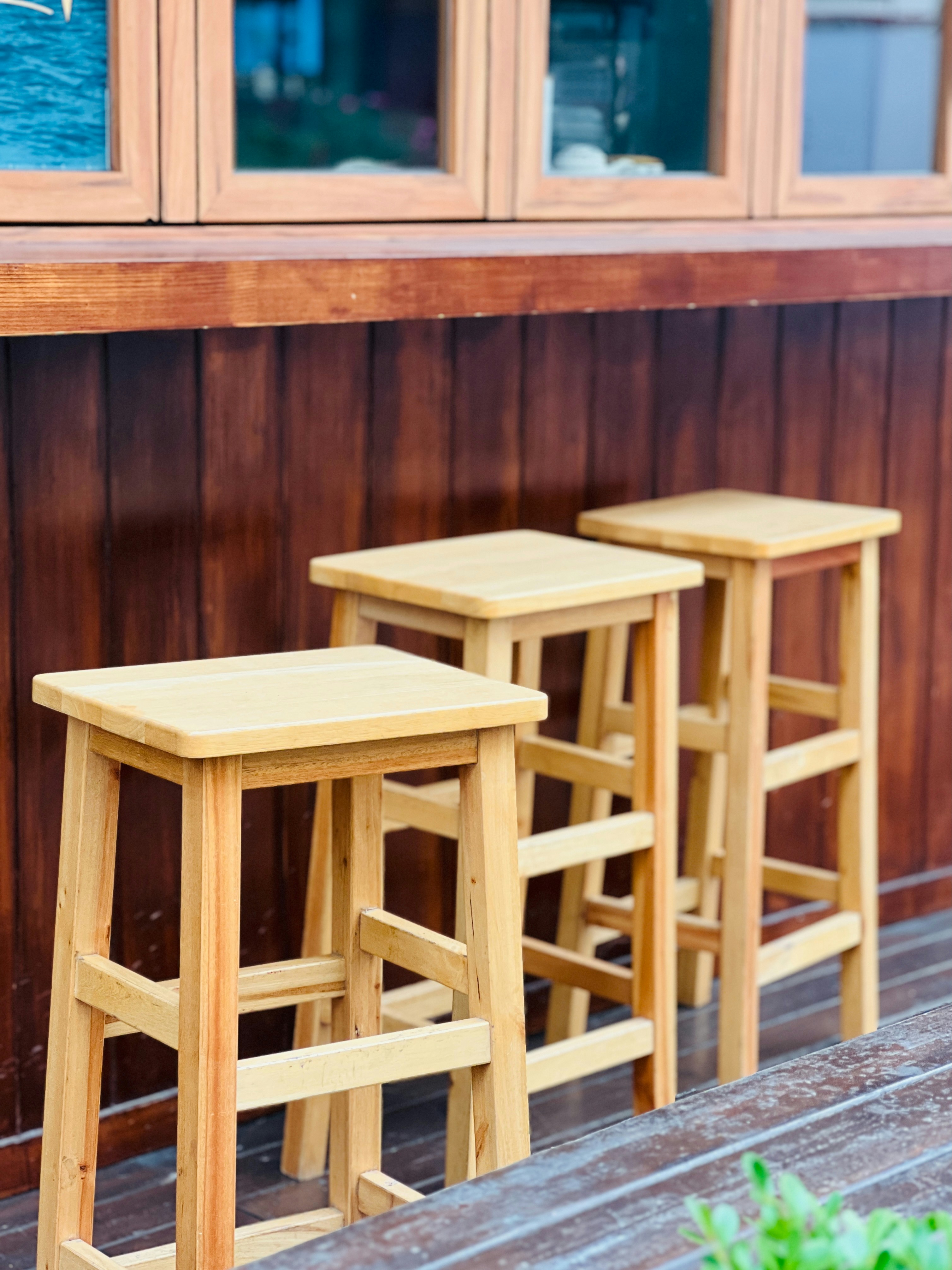 Drei Barhocker aus Holz, die in einer Reihe aufgereiht sind.