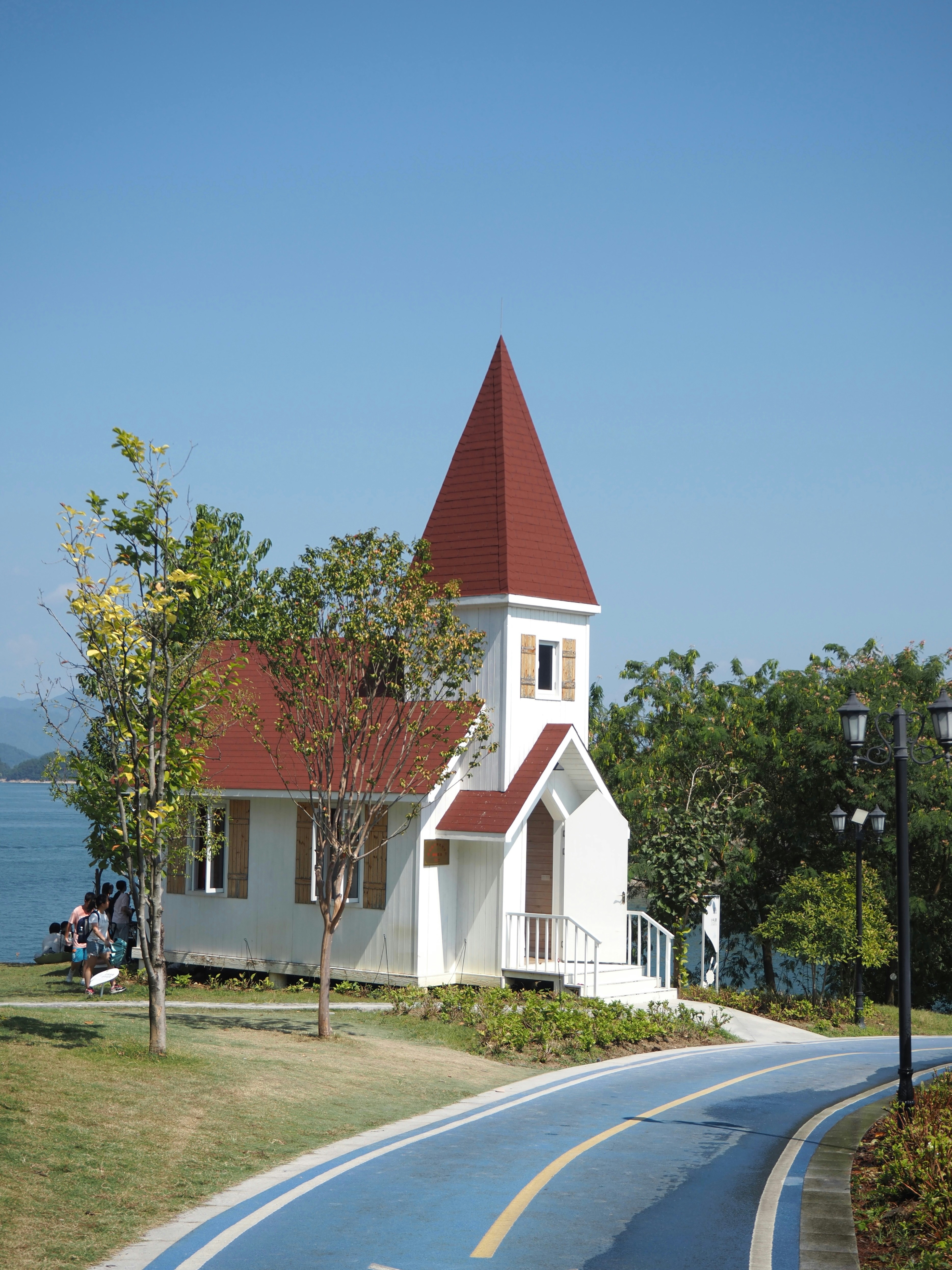 Petite église blanche avec toit rouge par chemin bleu