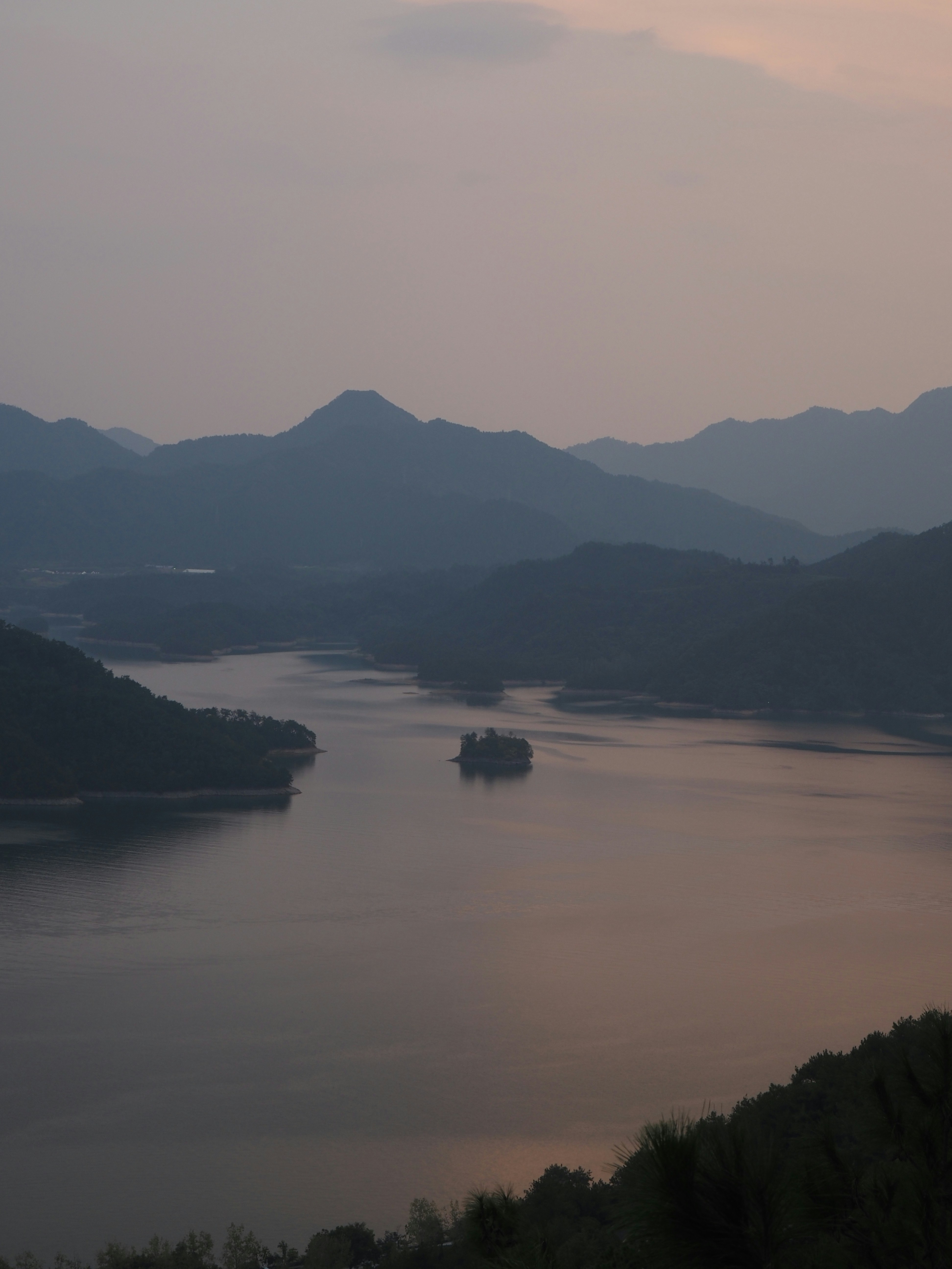 Lac serein avec des îles et des montagnes au crépuscule