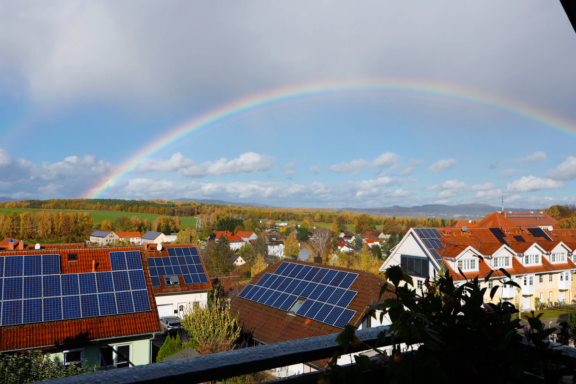 Rainbow over a suburban neighborhood with solar panels.
