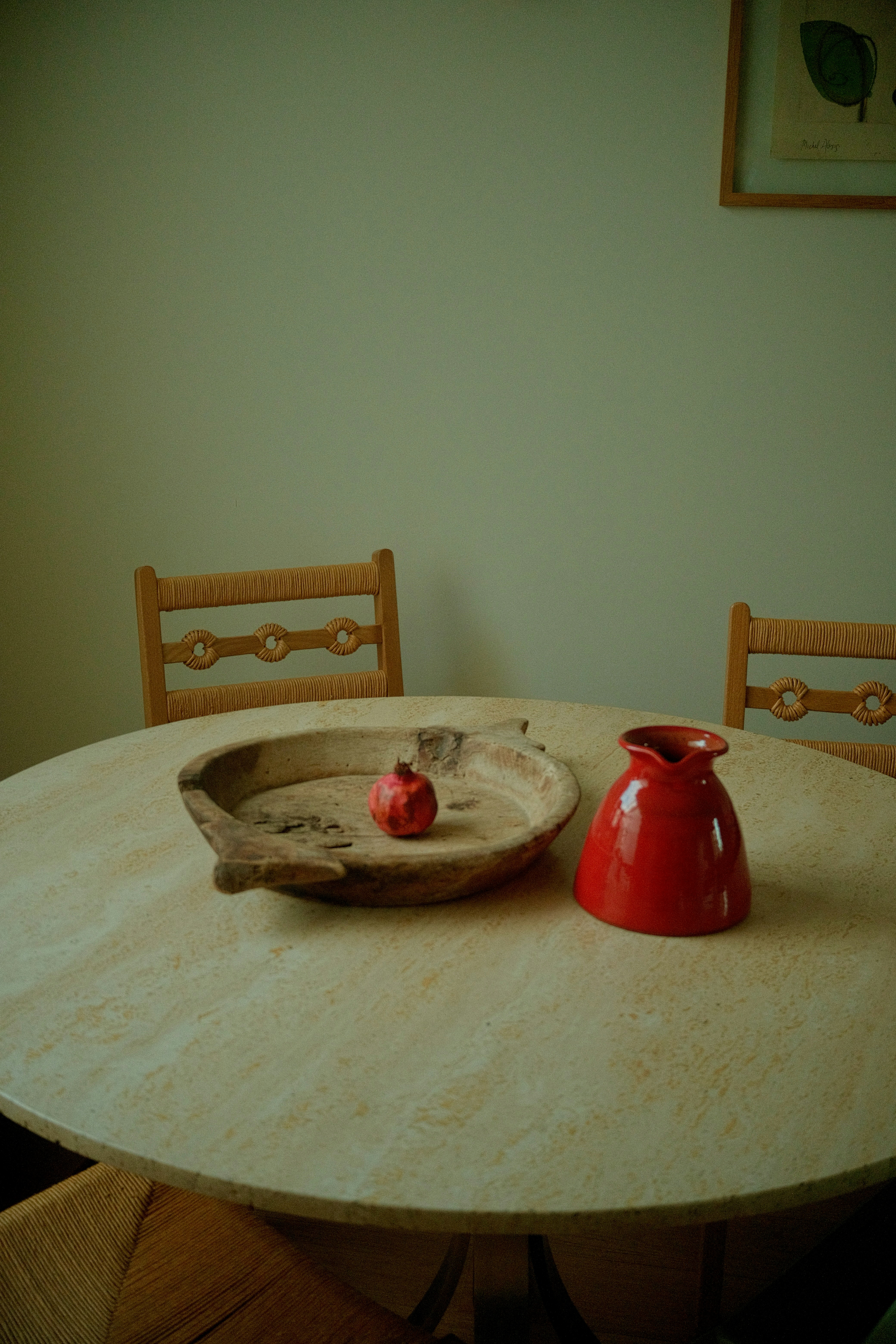 Wooden bowl with pomegranate and red vase on table