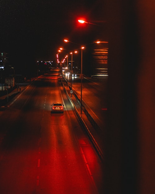 A car drives on a wet road at night.