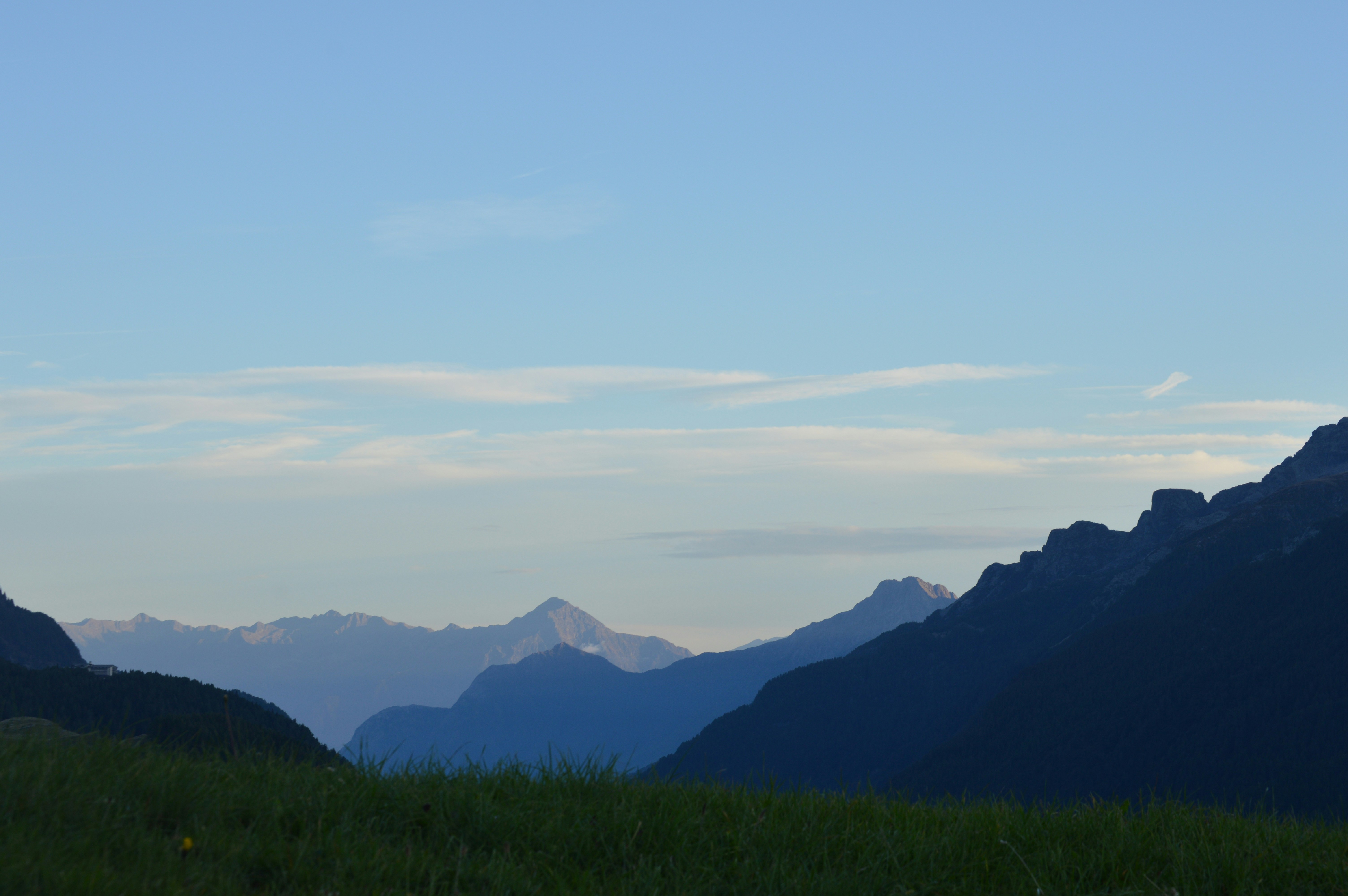 Silhouetted mountain ranges under a pale blue sky