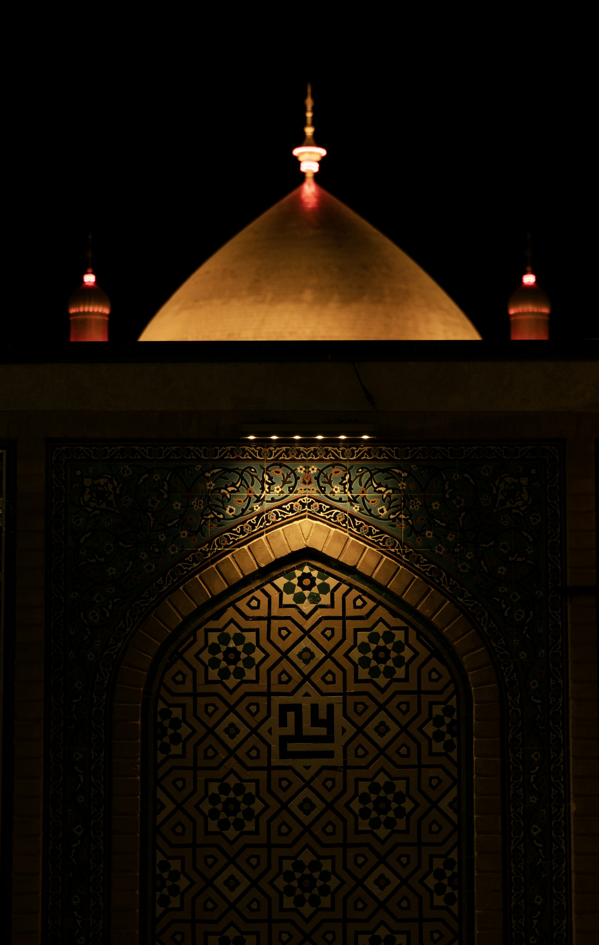 Golden dome illuminated at night with intricate tile work.