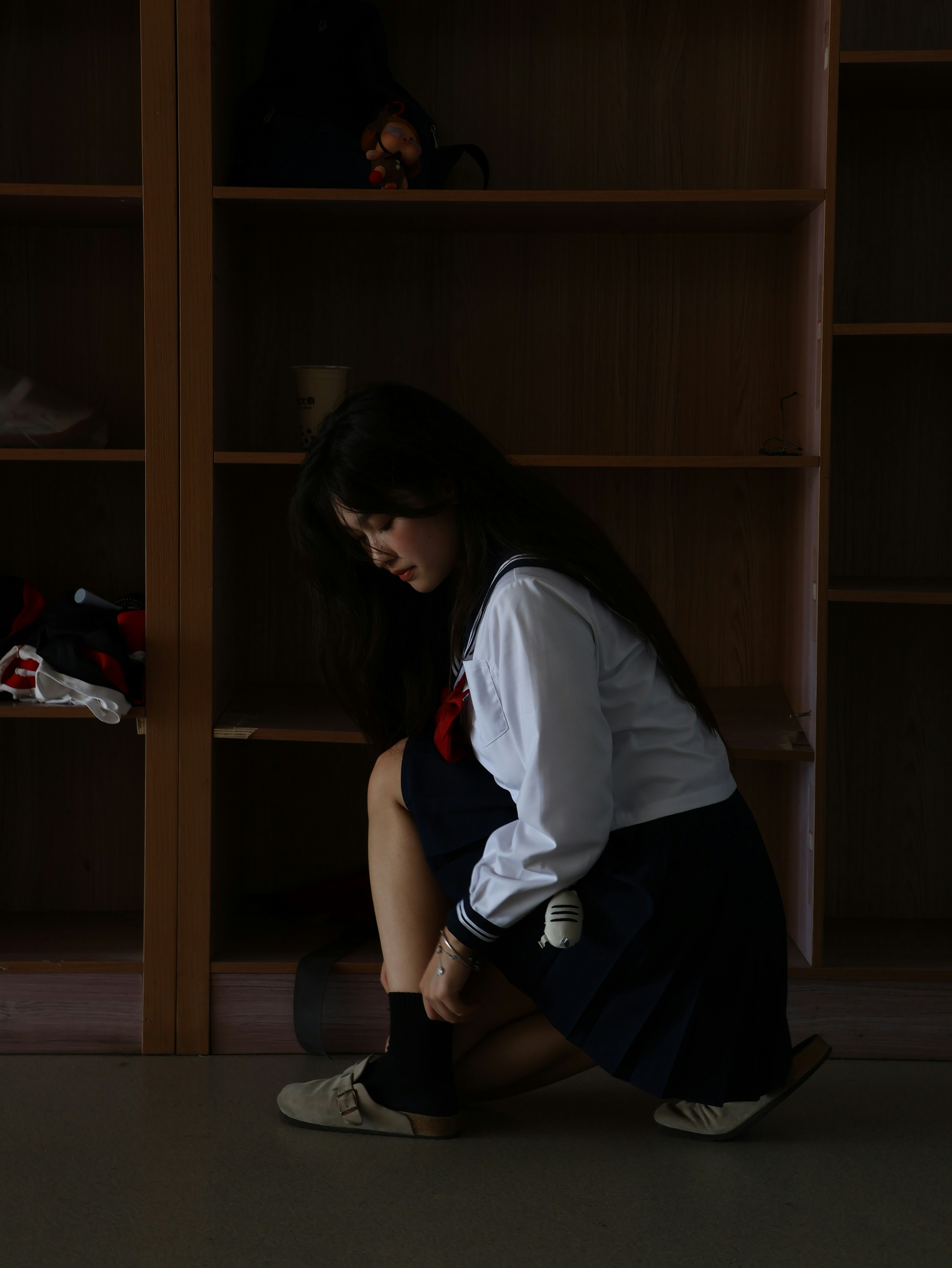 A student ties her shoes in a locker room.