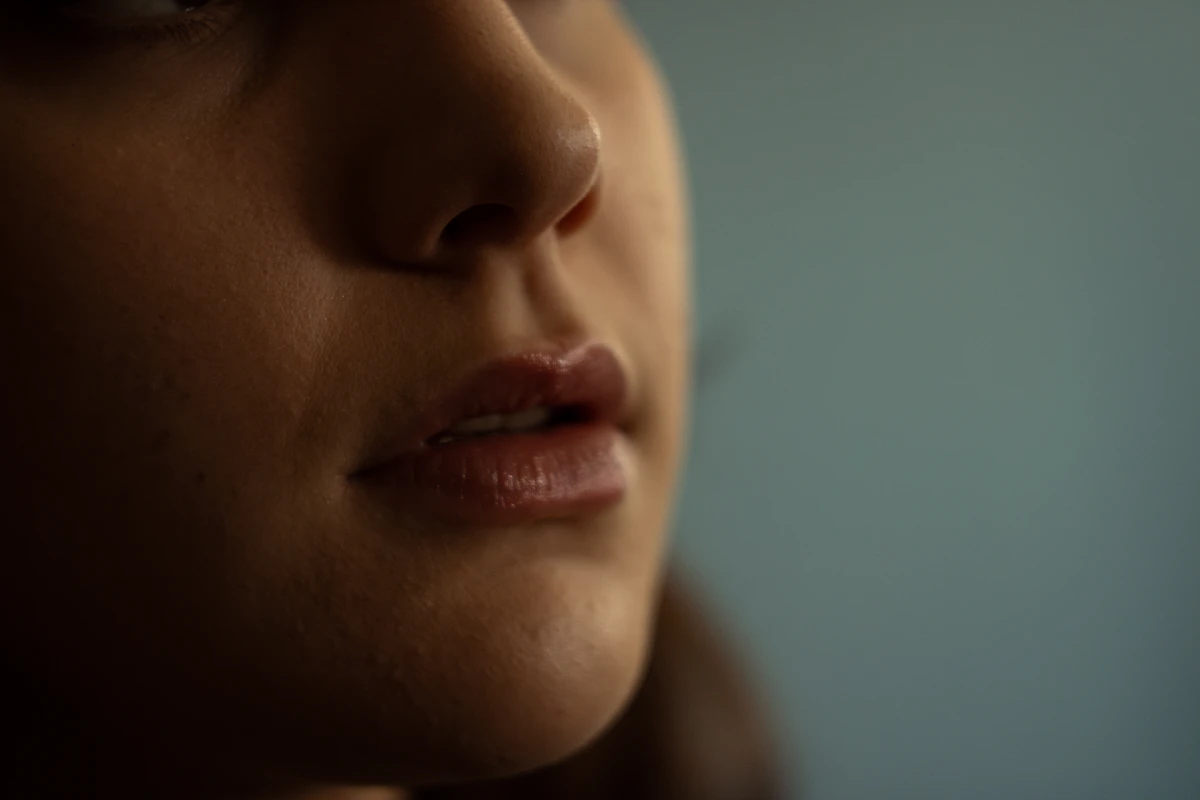 Close-up portrait of a young woman's lips in soft natural light, illustrating natural lip shape and proportion reviewed after lip filler treatment