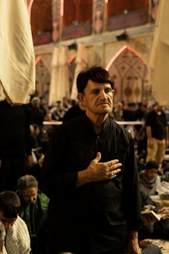 A man in black clothing with hand on chest