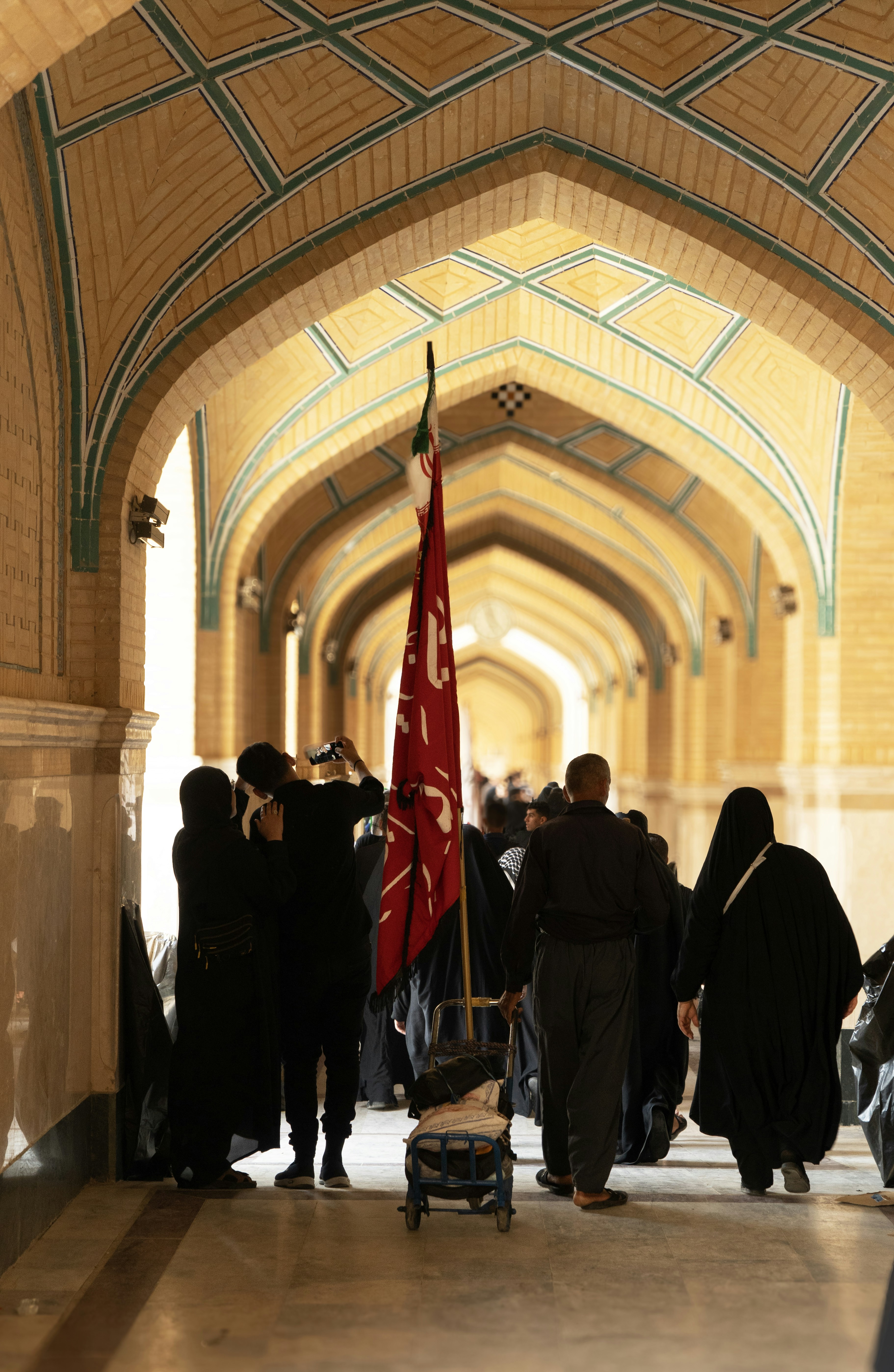 Gente caminando por un largo pasillo arqueado con una bandera.