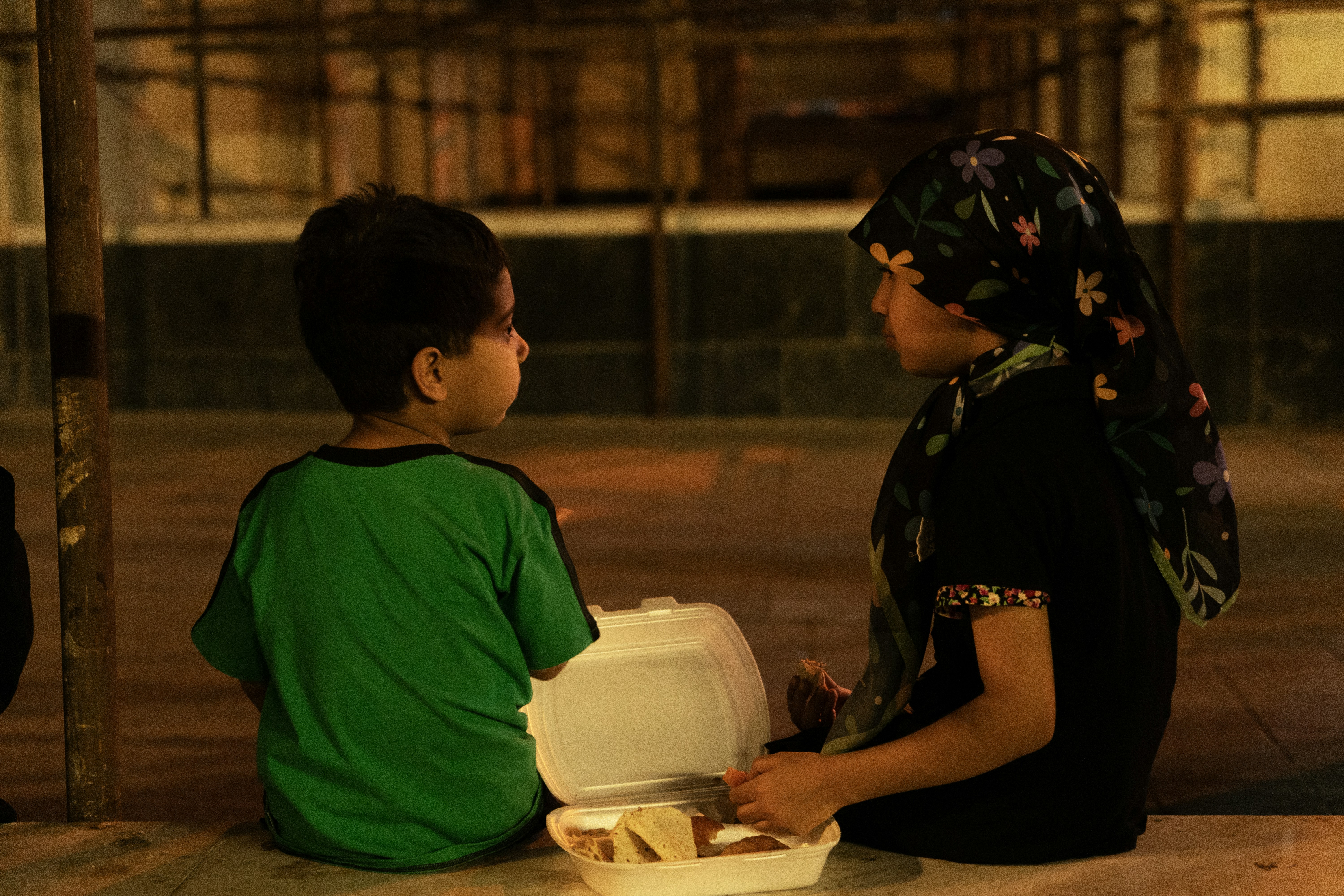 Dos niños compartiendo comida por la noche.