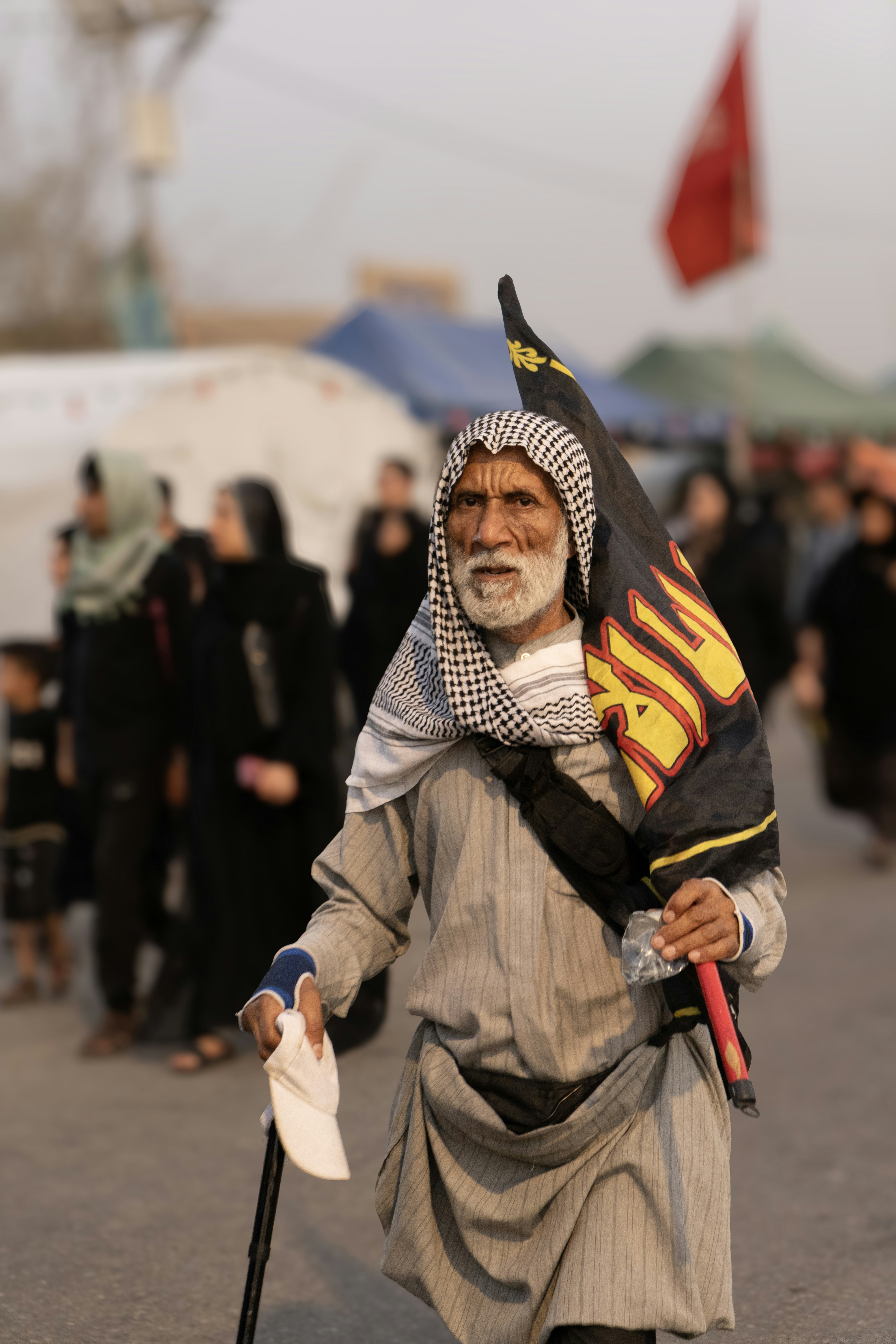 Anciano con bandera caminando con un bastón