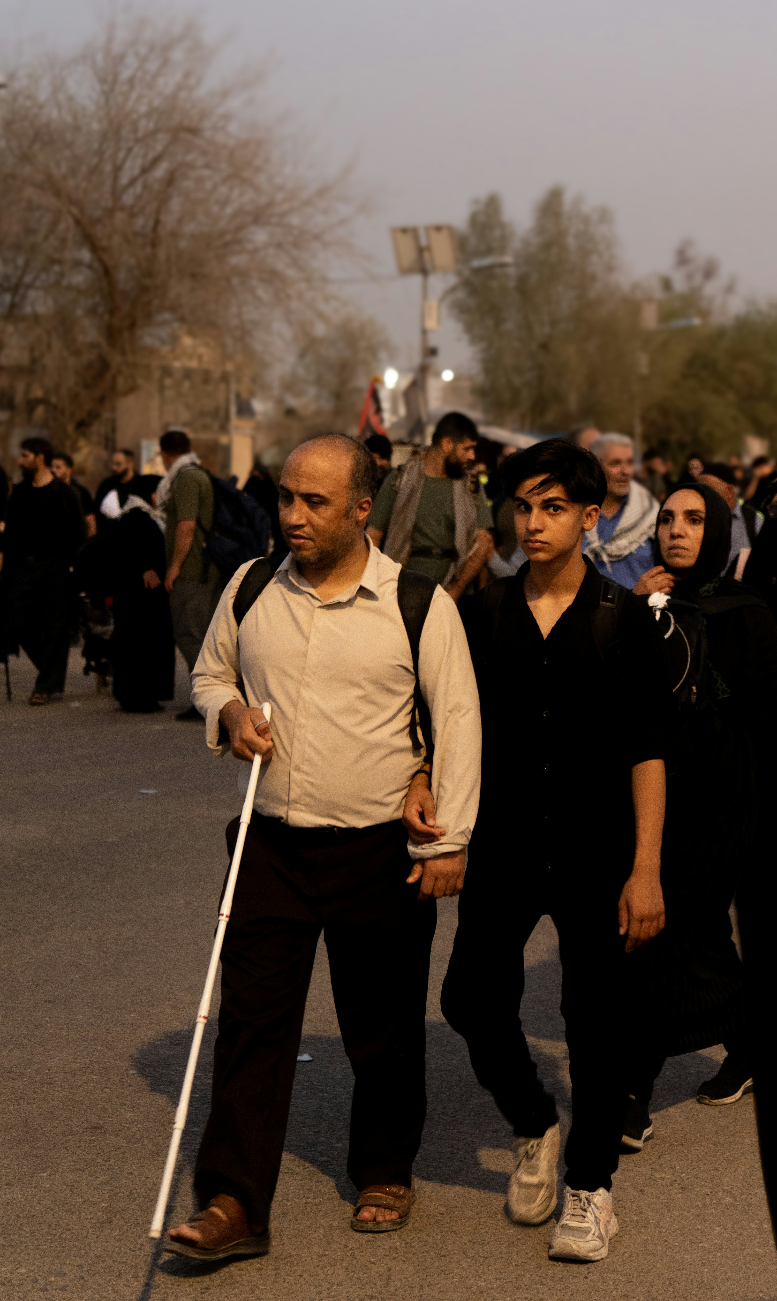 Un hombre con un bastón camina con una persona más joven.